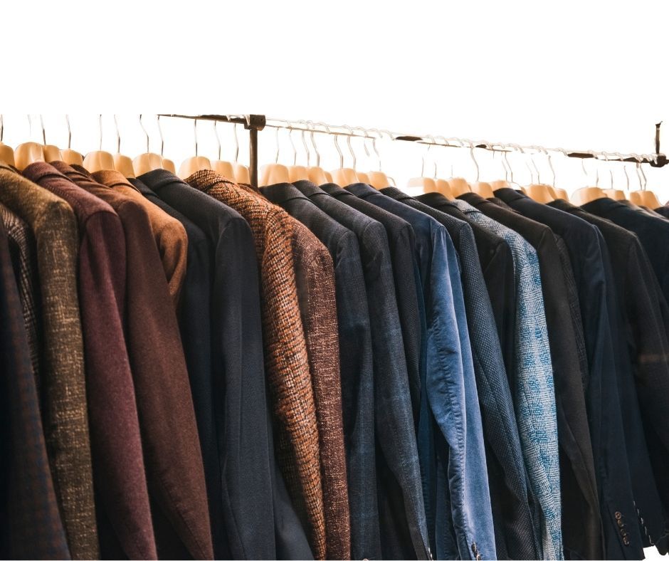 A row of winter coats and jackets hanging on a clothing rack in earth tones and dark colors.