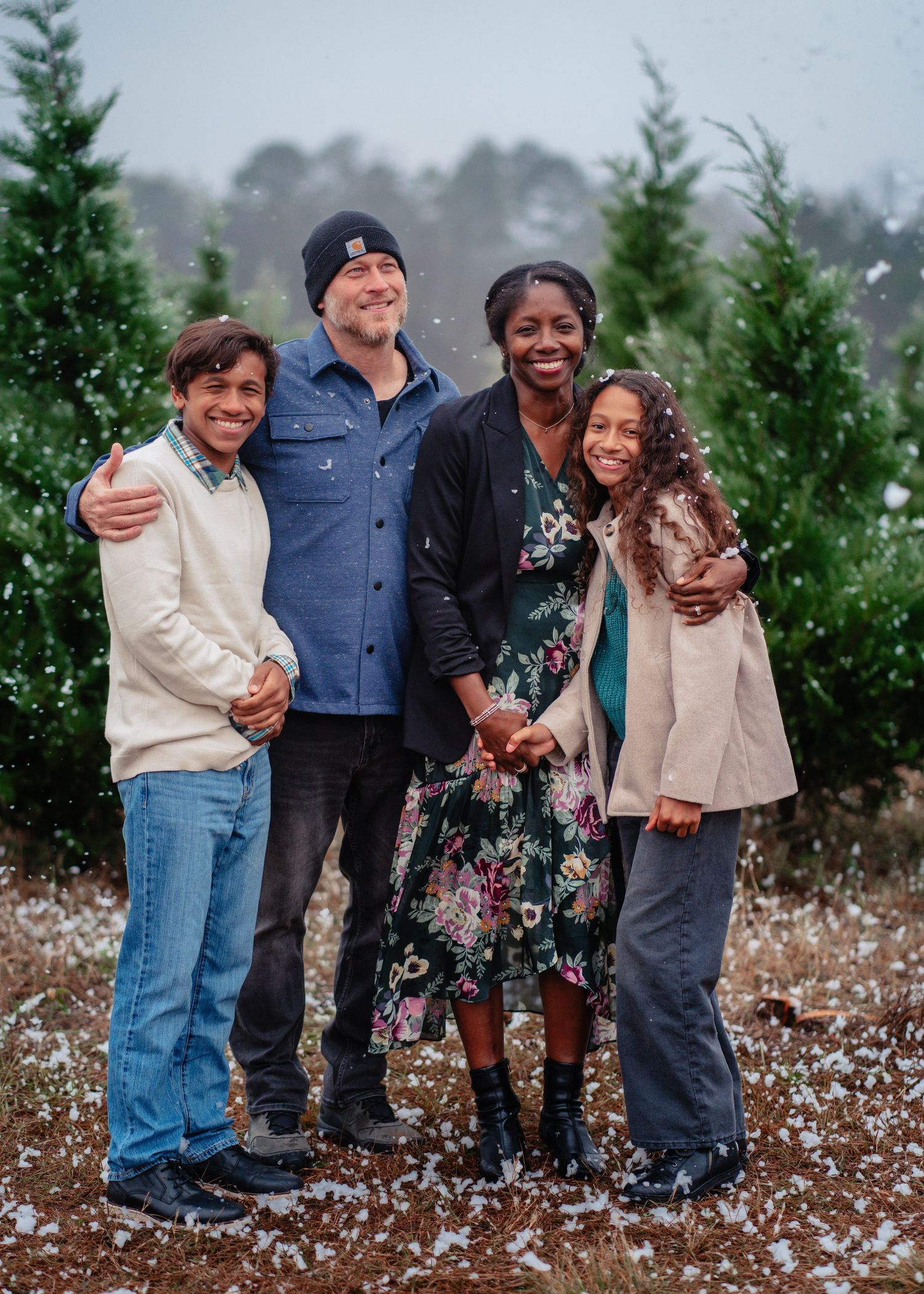 A family shares joyful moments together while posing in a cotton field on a cloudy day.