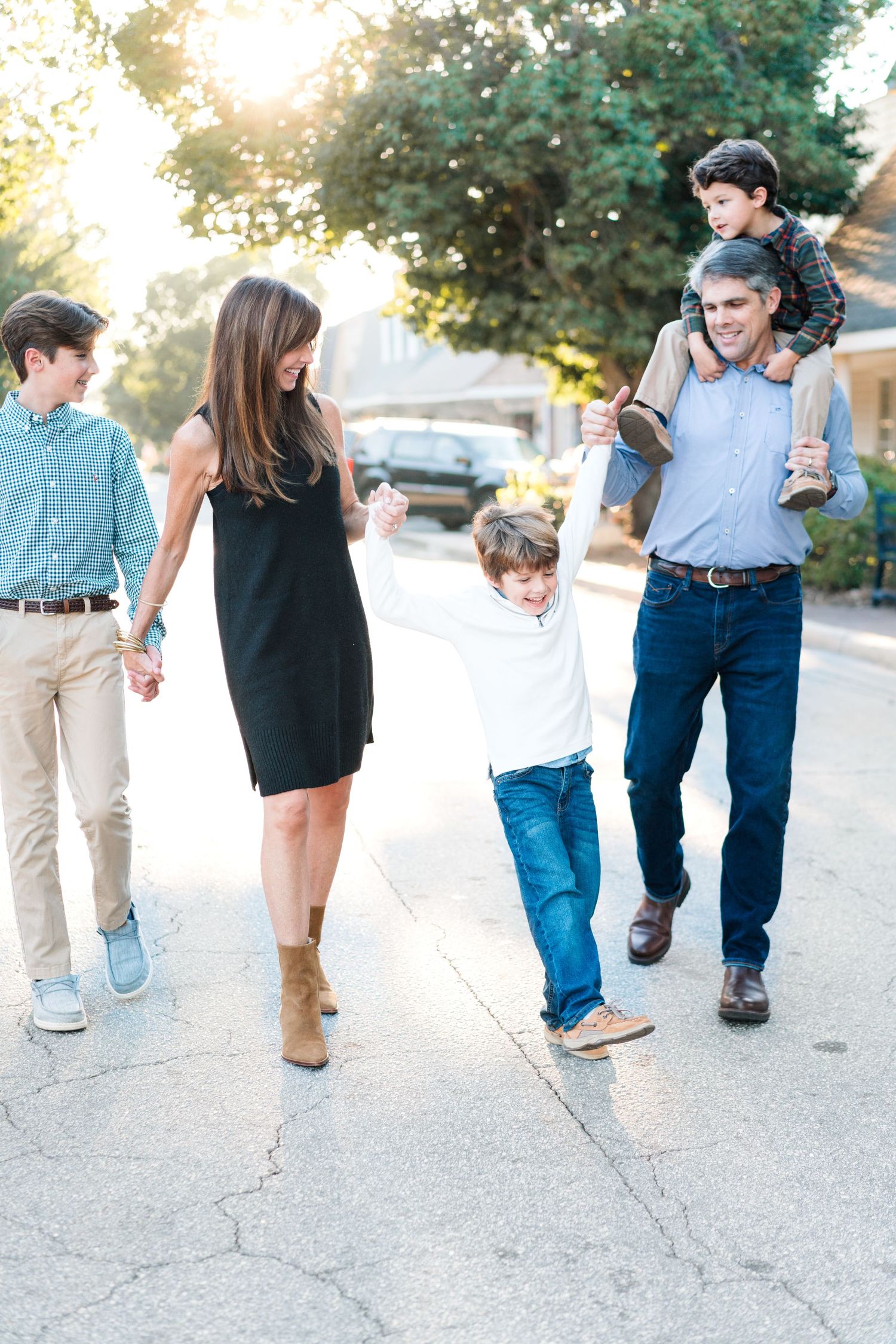 Family walking together on sidewalk during golden hour, captured in casual motion.