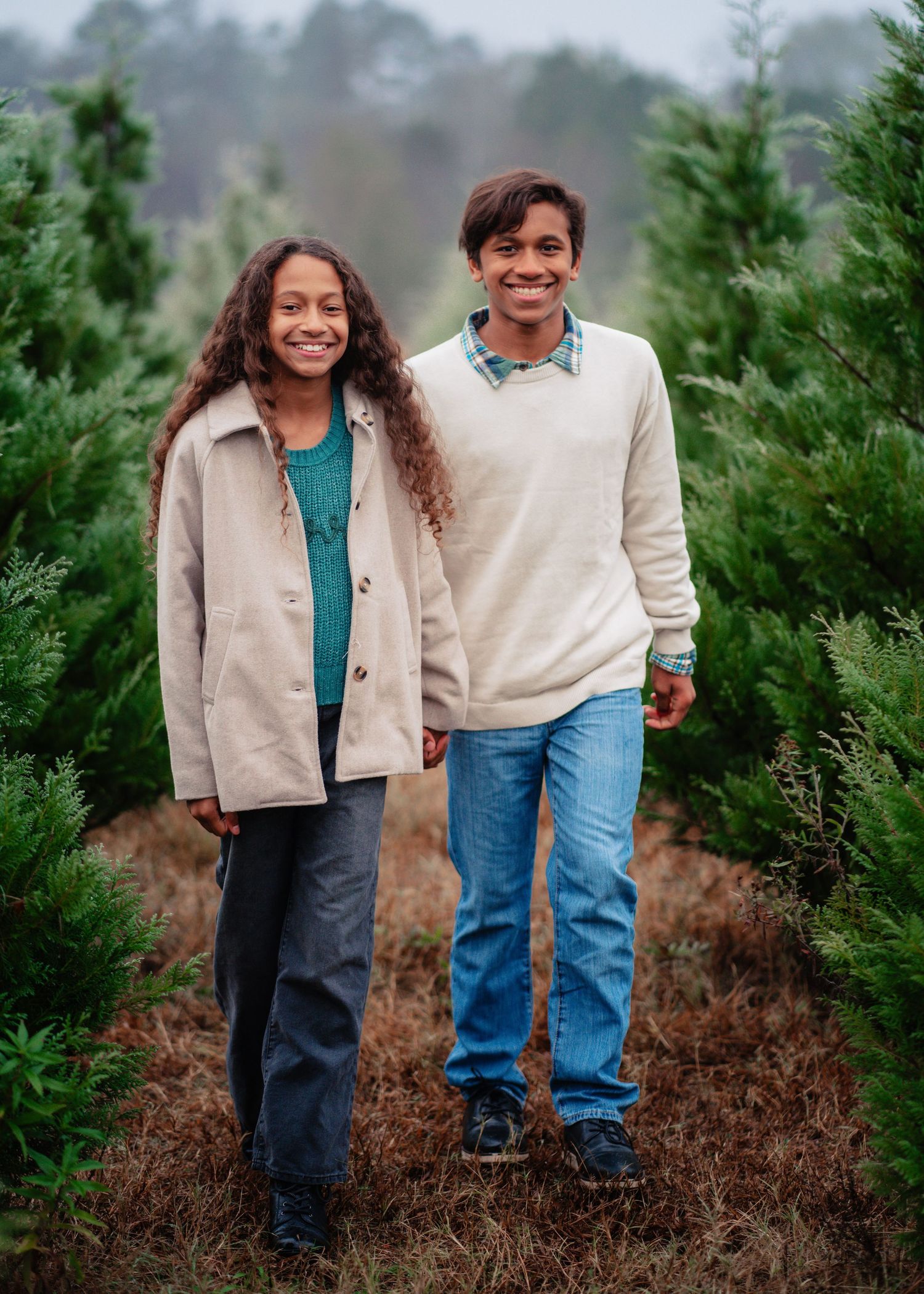 A series of four candid photos showing a pair in matching beige and blue outfits standing among evergreen trees.