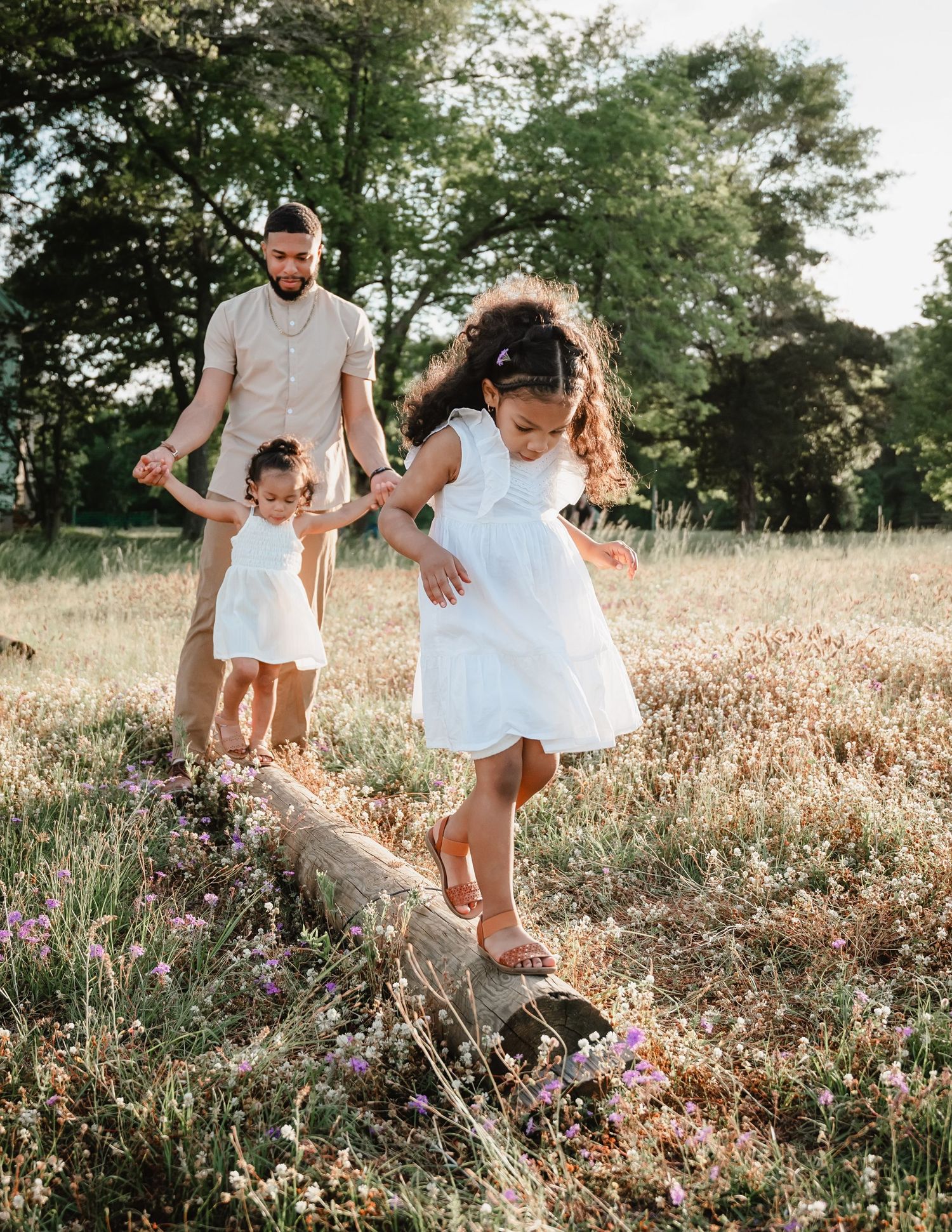 A family plays together in a sun-drenched wildflower field during golden hour.