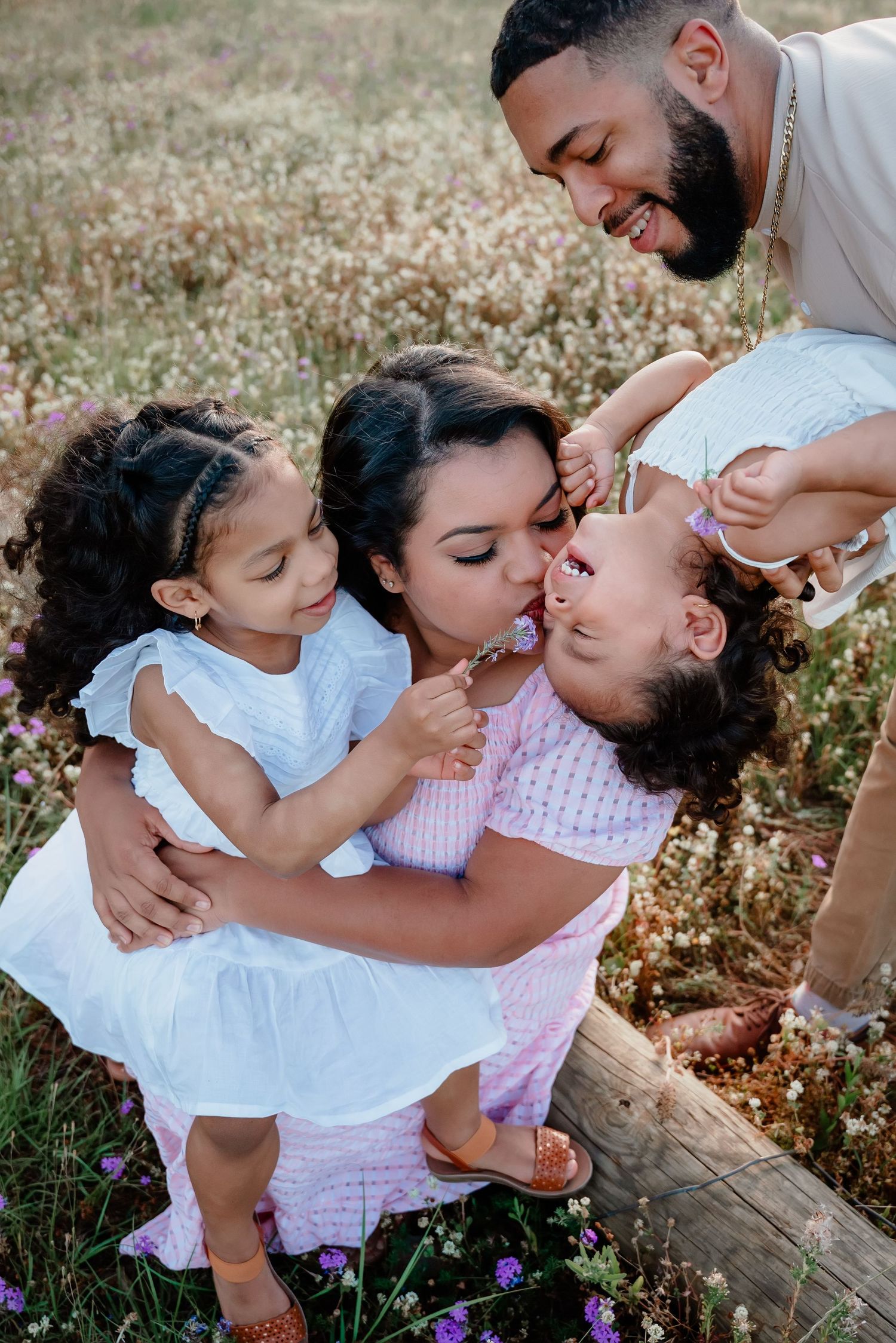 A loving family shares joyful moments together while sitting in a wildflower field during golden hour.