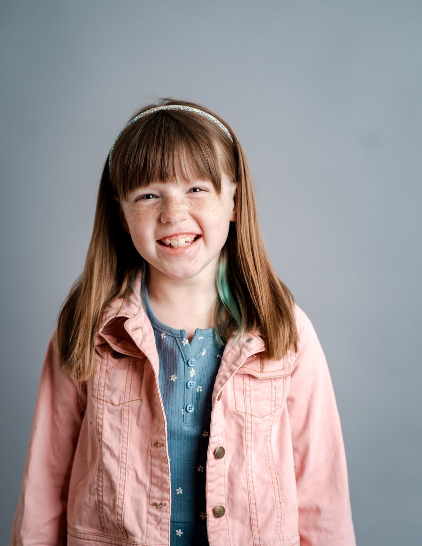 A series of portraits showing a person wearing a pink denim jacket and blue shirt against a gray background.