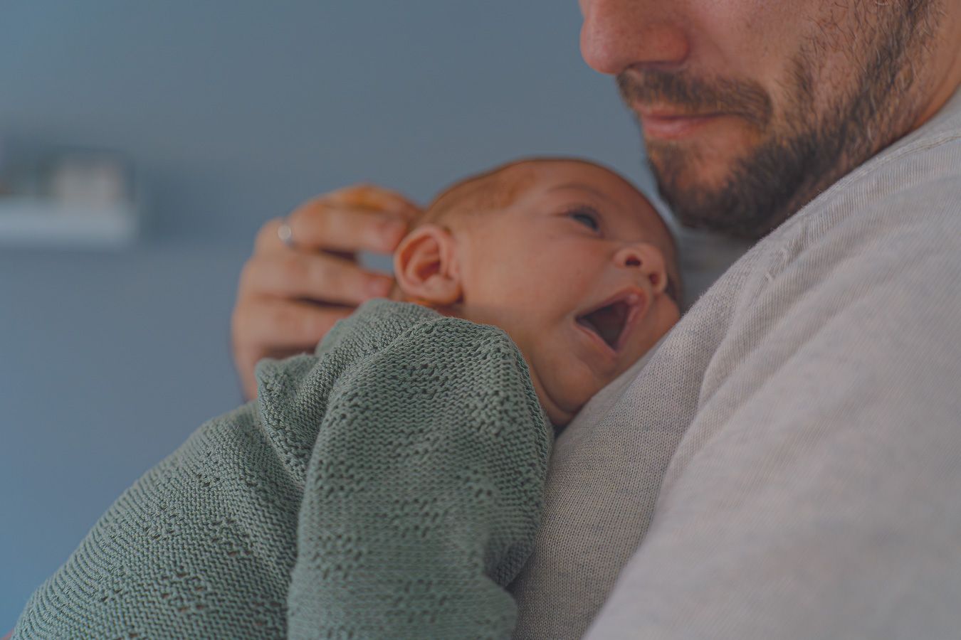 Padre abrazando a su bebé recién nacido. Reportaje de fotografía newborn a domicilio en Barcelona. Sesión familiar lifestyle natural.