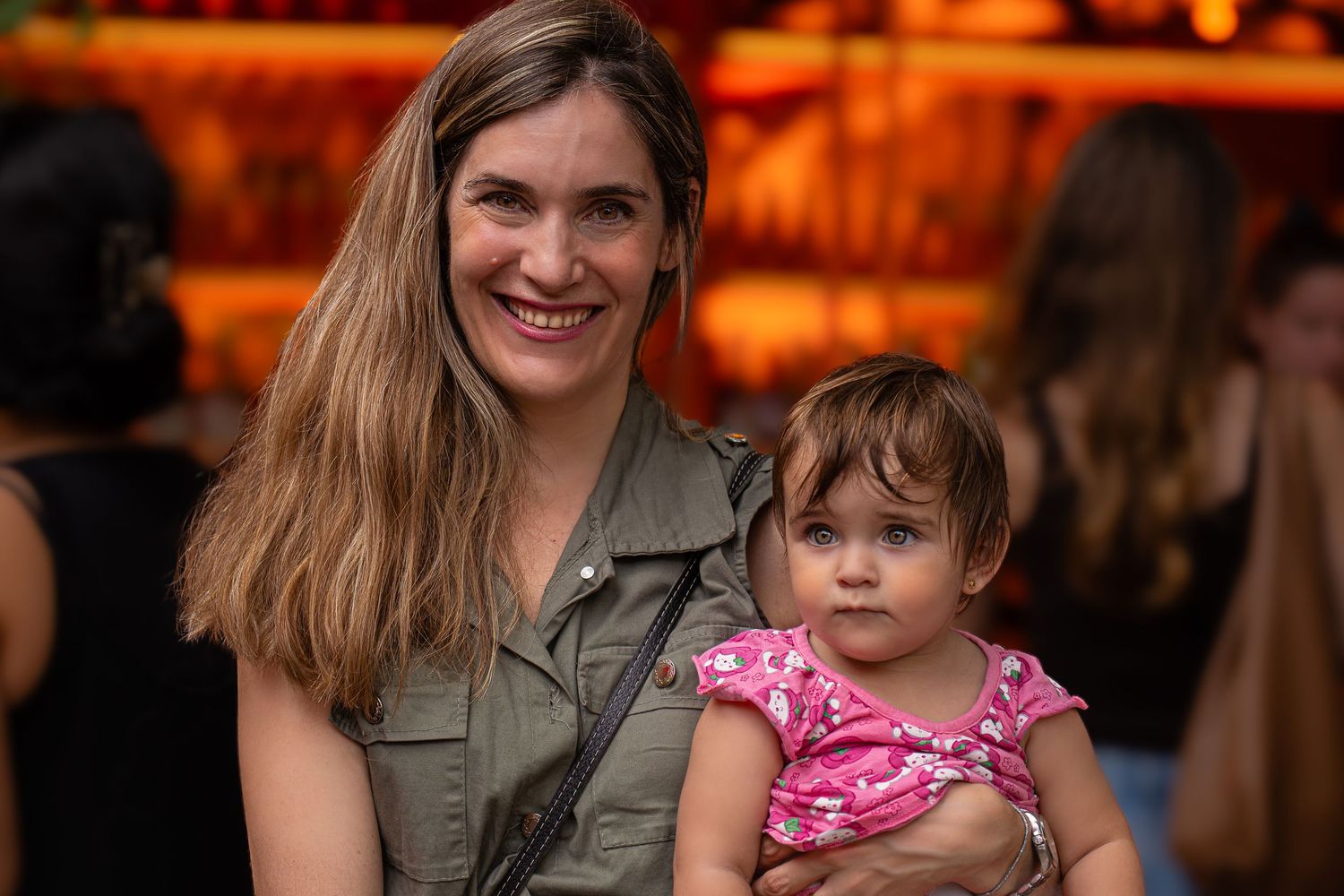 Madre e hija comparten un tierno momento juntos bajo una cálida iluminación, con sonrisas a juego.