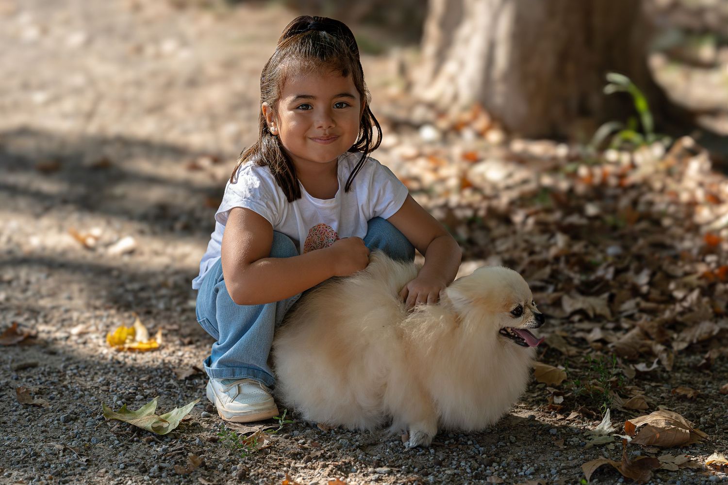 Niña feliz abraza a su perro samoyedo en la naturaleza con hojas secas de otoño, sesión de fotos lifestyle con mascotas, fotografía Meraki