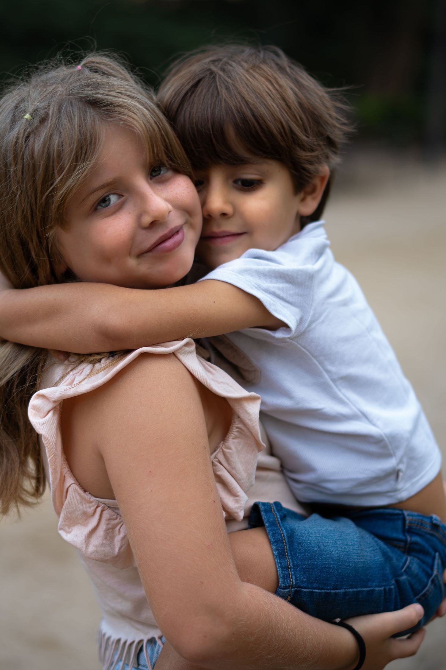 Un tierno abrazo entre hermanos vestidas de blanco y vaqueros en una serie de fotos espontáneas al aire libre.