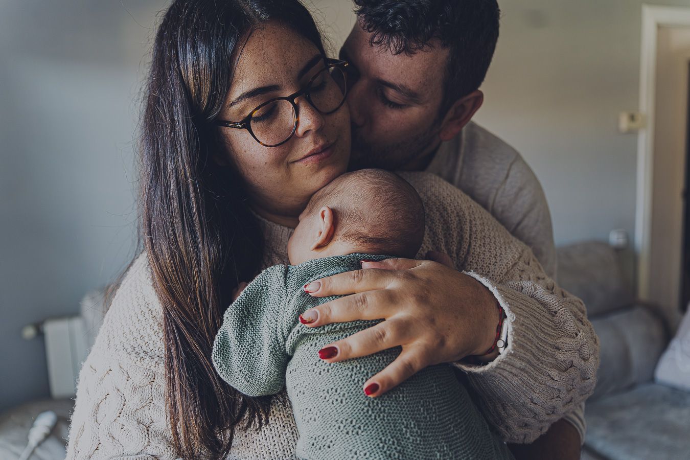 Padres abrazando con ternura a su bebé recién nacido, fotografía de familia lifestyle y sin posados en Sant Cugat, estilo Meraki.