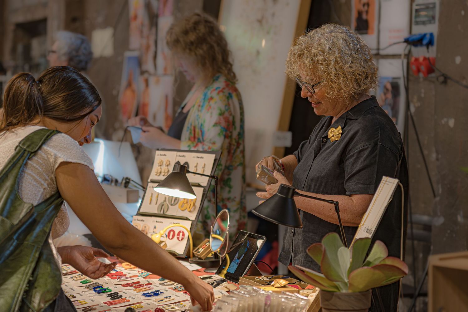 Un grupo de artistas trabaja diligentemente en mesas durante una sesión de taller creativo en un estudio de arte.