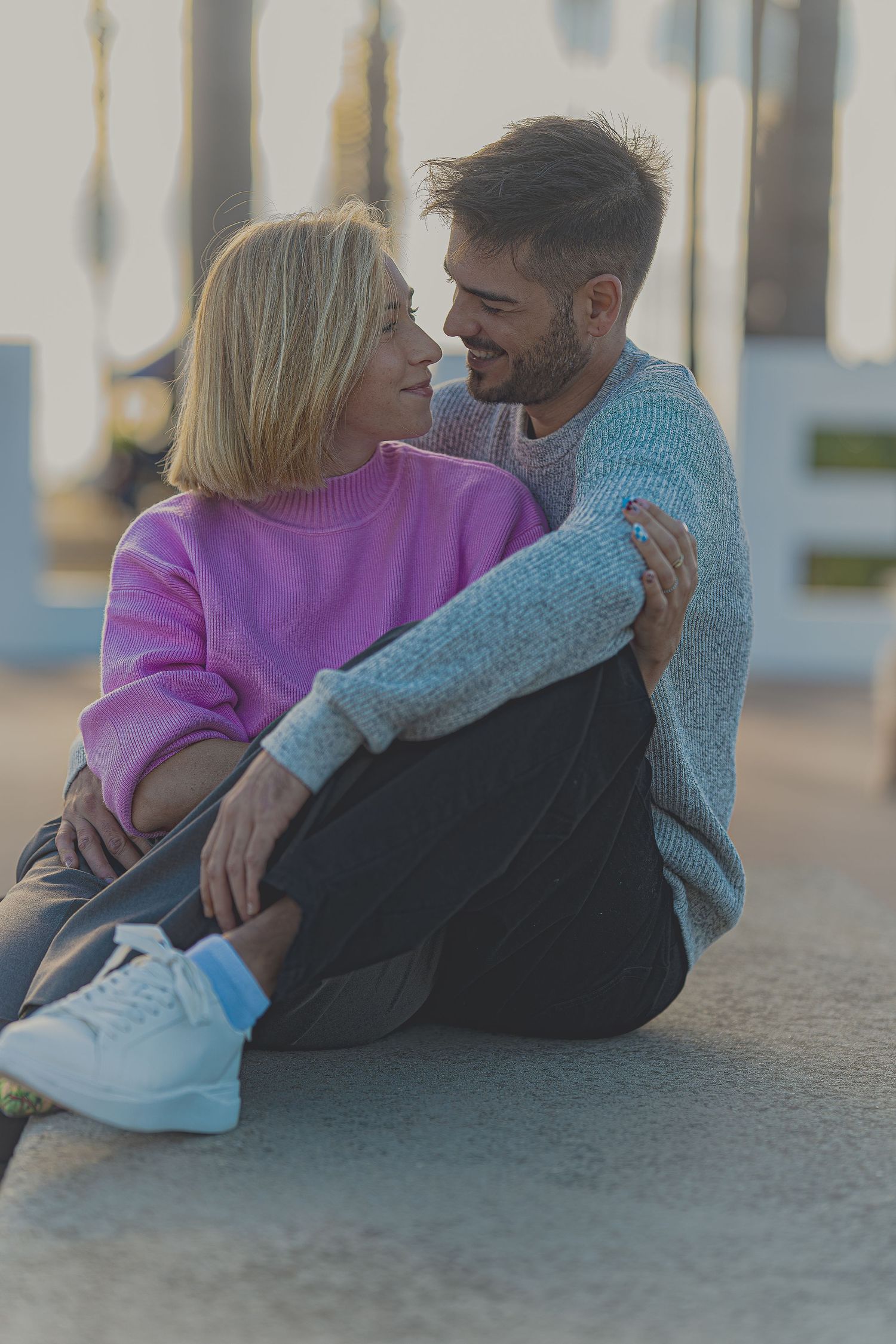 Pareja joven abrazándose cariñosamente sentados en el suelo al atardecer, fotografía de pareja lifestyle en Barcelona, Meraki by Vgracia