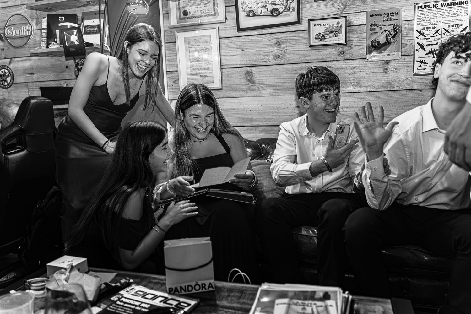 Black and white photo of young people socializing at a casual party inside a rustic bar setting.