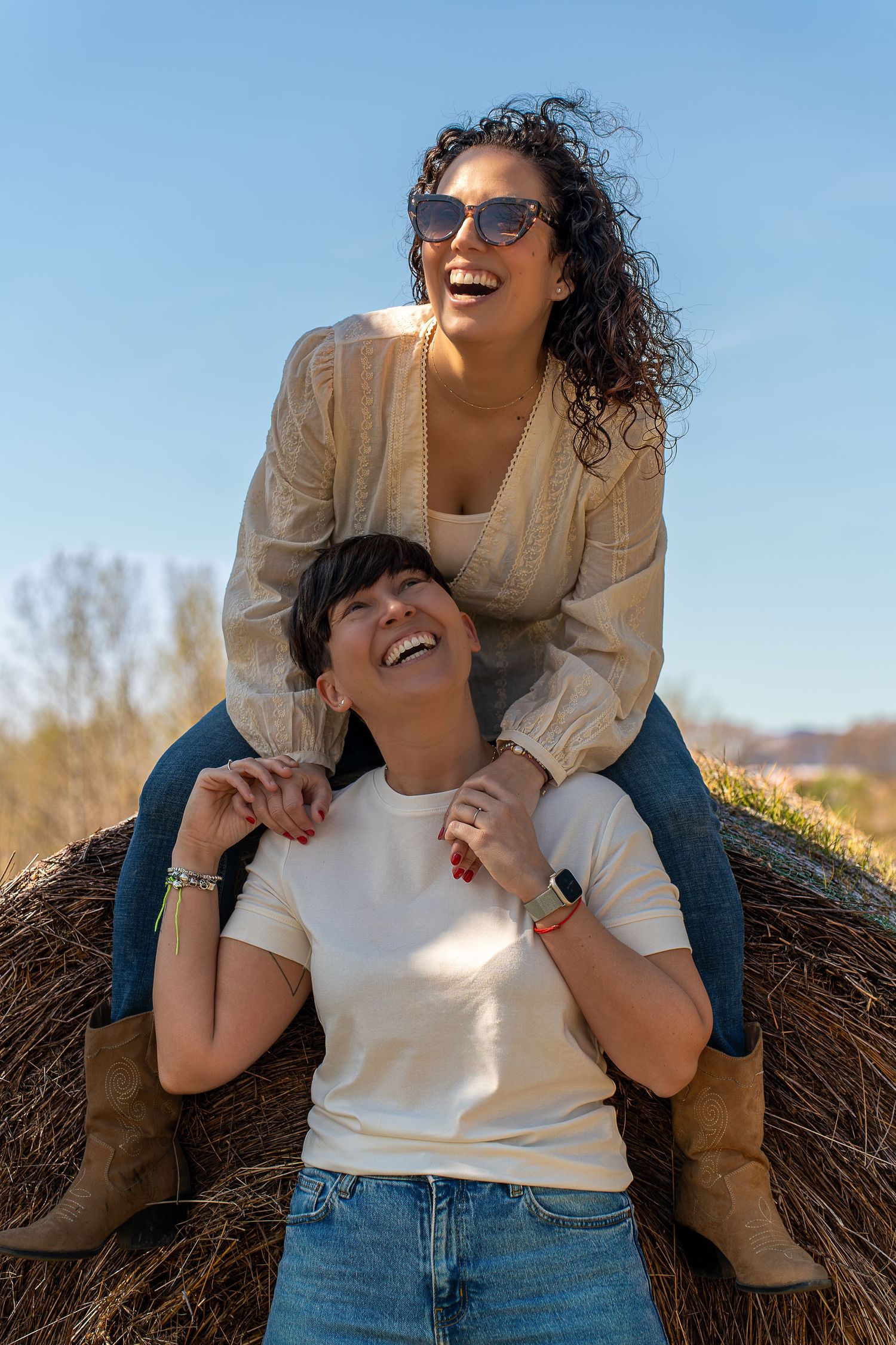 Pareja de chicas riendo a carcajadas durante su sesión de fotos preboda inclusiva en Barcelona, luz de mañana, estilo Meraki.