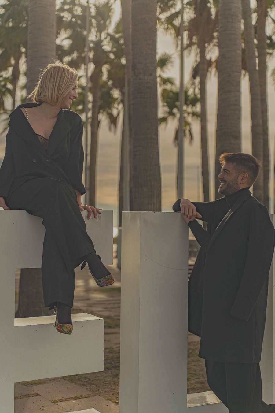 Sesión de fotografía de pareja con dos modelos a contraluz con sol de atardecer y trajes negros -Meraki by VGracia