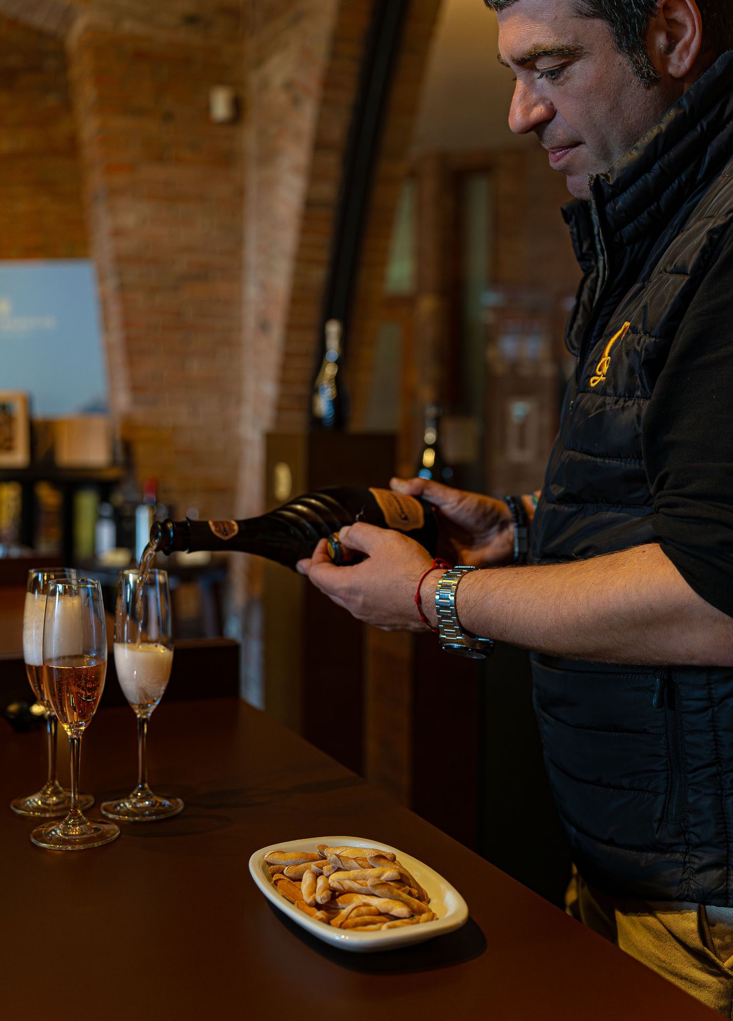 Una secuencia de fotos que muestran copas de cava y platos servidos en la tienda de unas cavas  con restaurante con paredes de ladrillo.