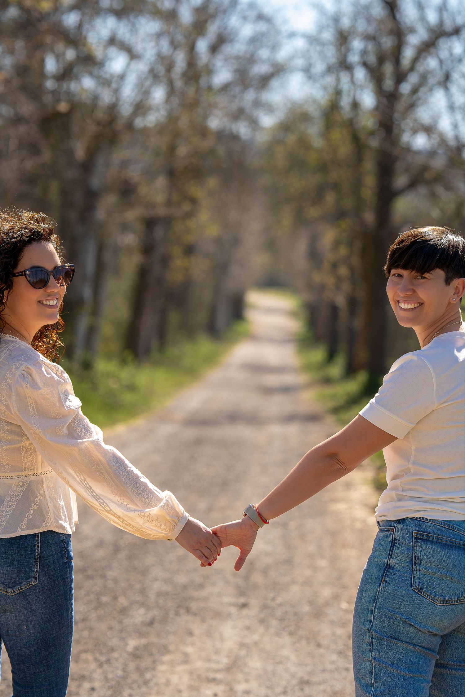 Dos mujeres paseando de la mano por la naturaleza, fotografía de pareja casual y natural en Sant Cugat.