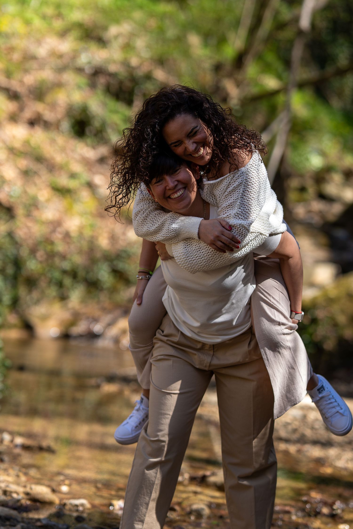 Pareja de chicas divirtiéndose en el bosque jugando a caballito. Sesión preboda natural y lifestyle en Sant Cugat del Vallès.