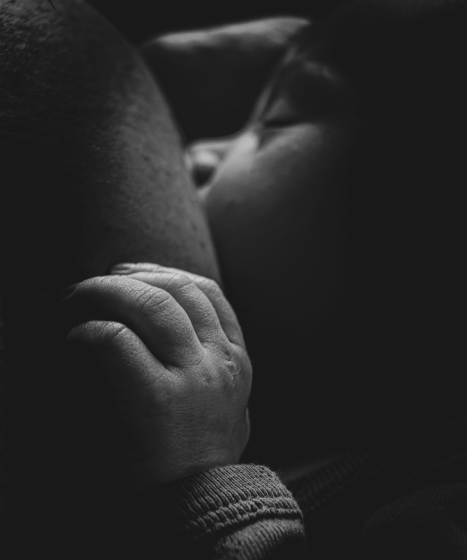 Detalle en blanco y negro de manita de bebé recién nacido sobre el pecho. Sesión newborn documental y natural en Sant Cugat.