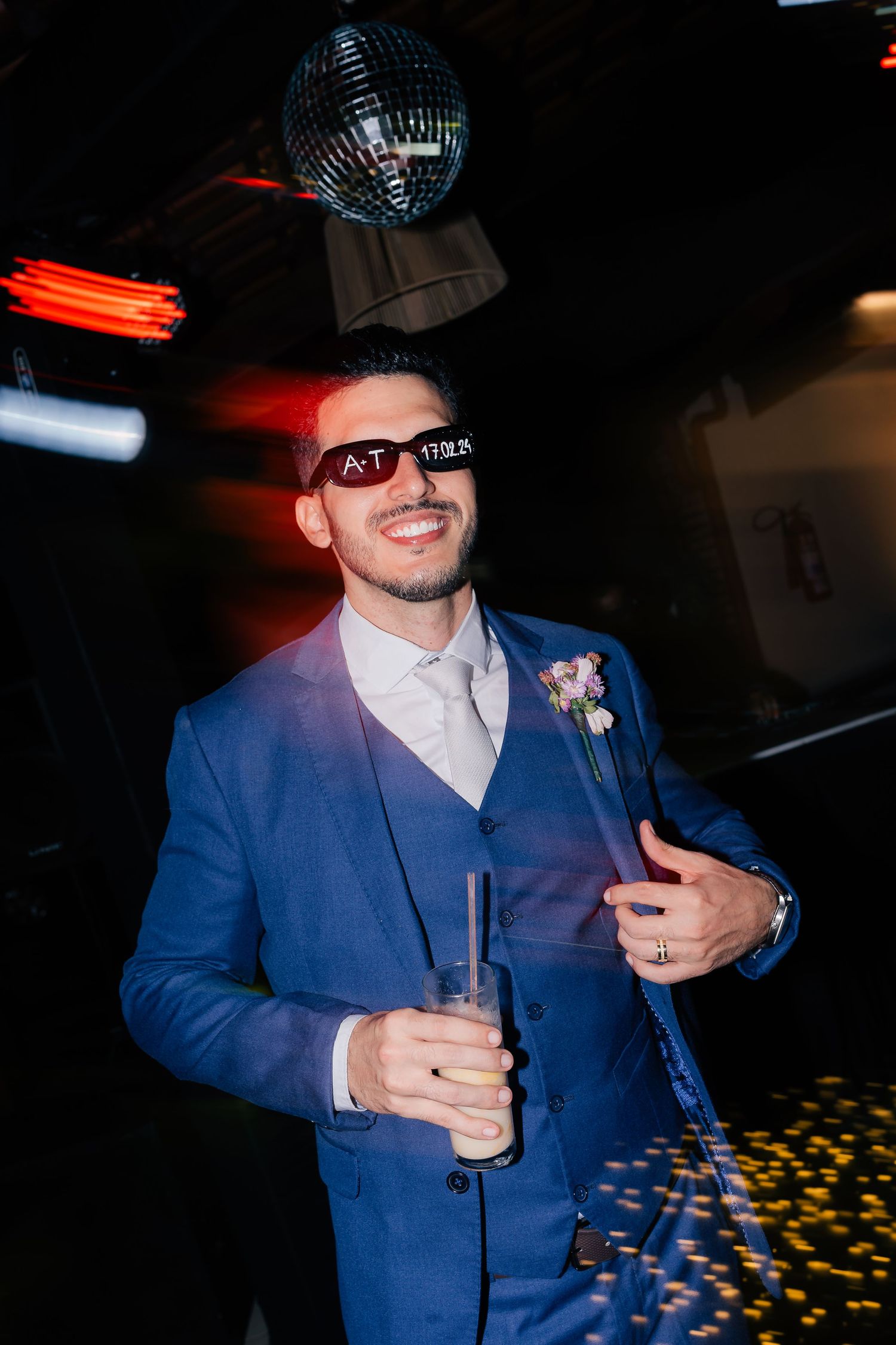 Person in blue suit dancing under a disco ball at a nightclub party.