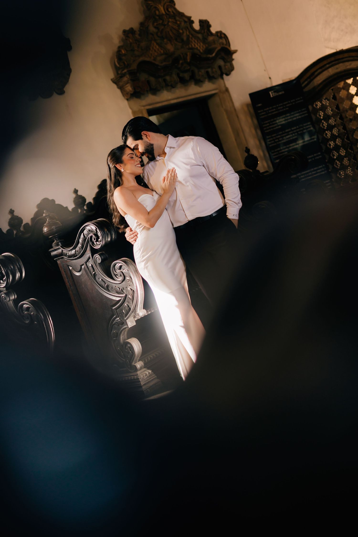 Silhouetted couple dancing in a dimly lit venue with ornate wall decorations visible in the background.