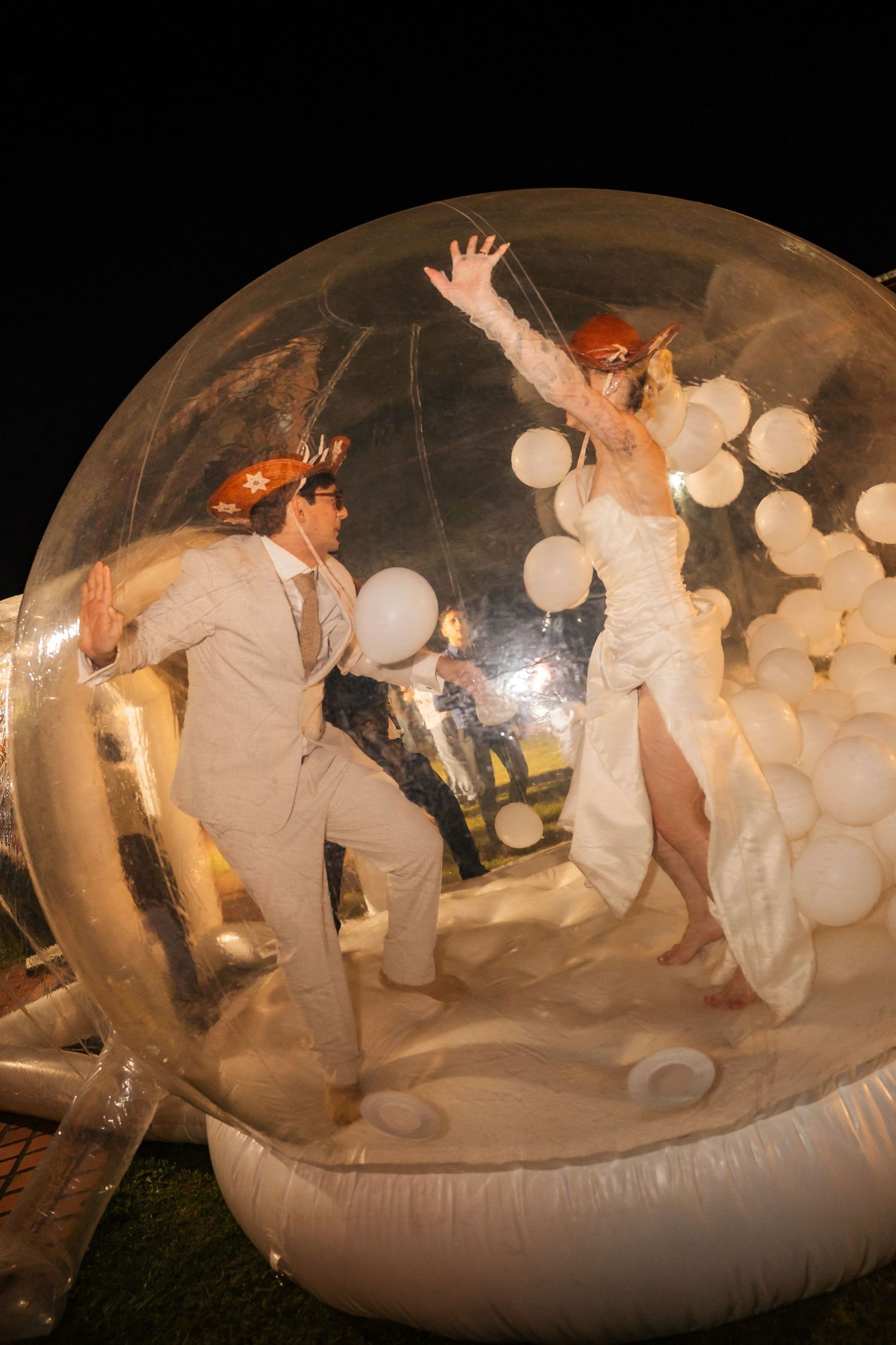 Wedding couple dances inside clear inflatable bubble with glowing lights.