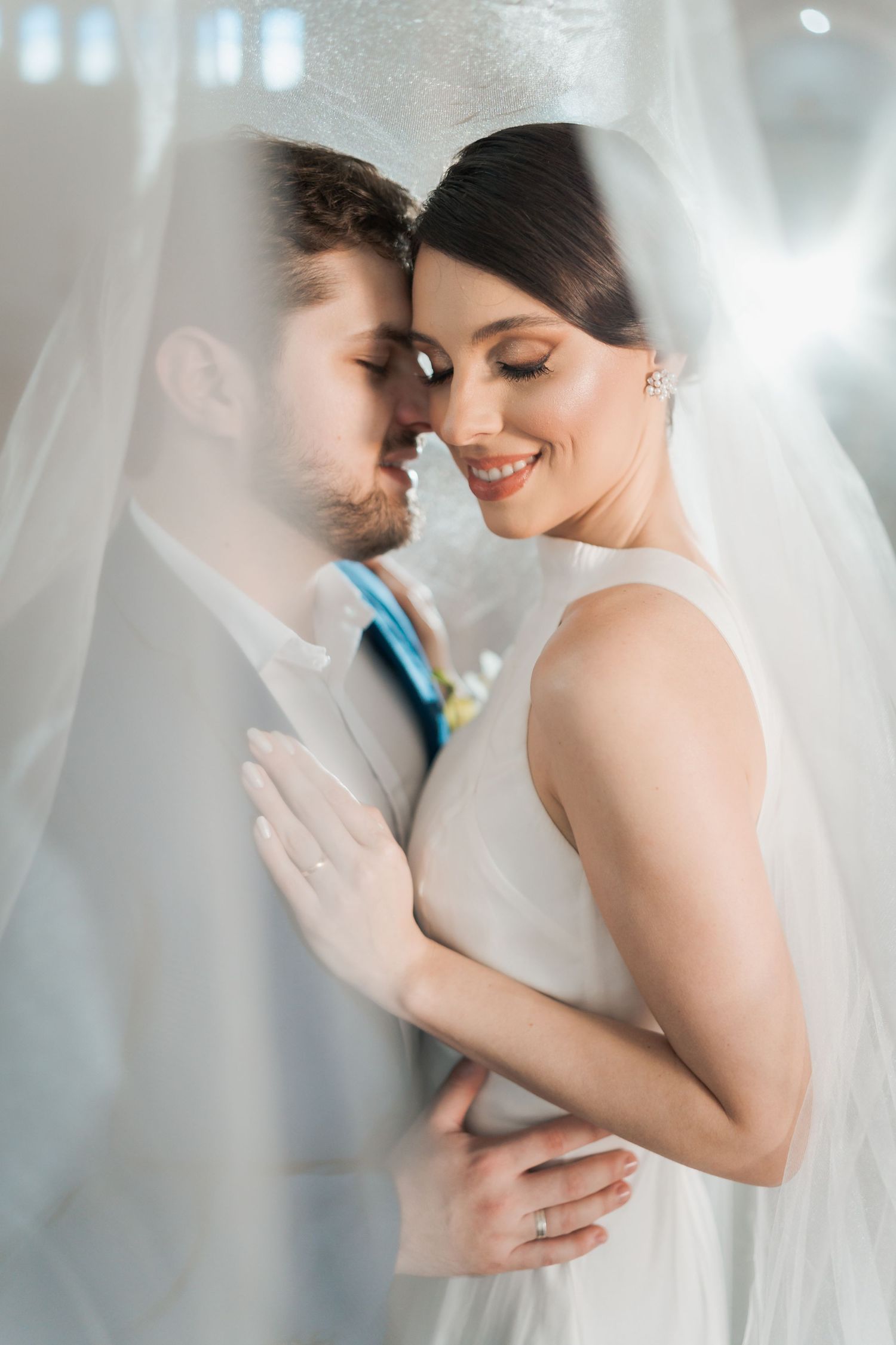 An intimate wedding portrait moment captured through delicate white veil.