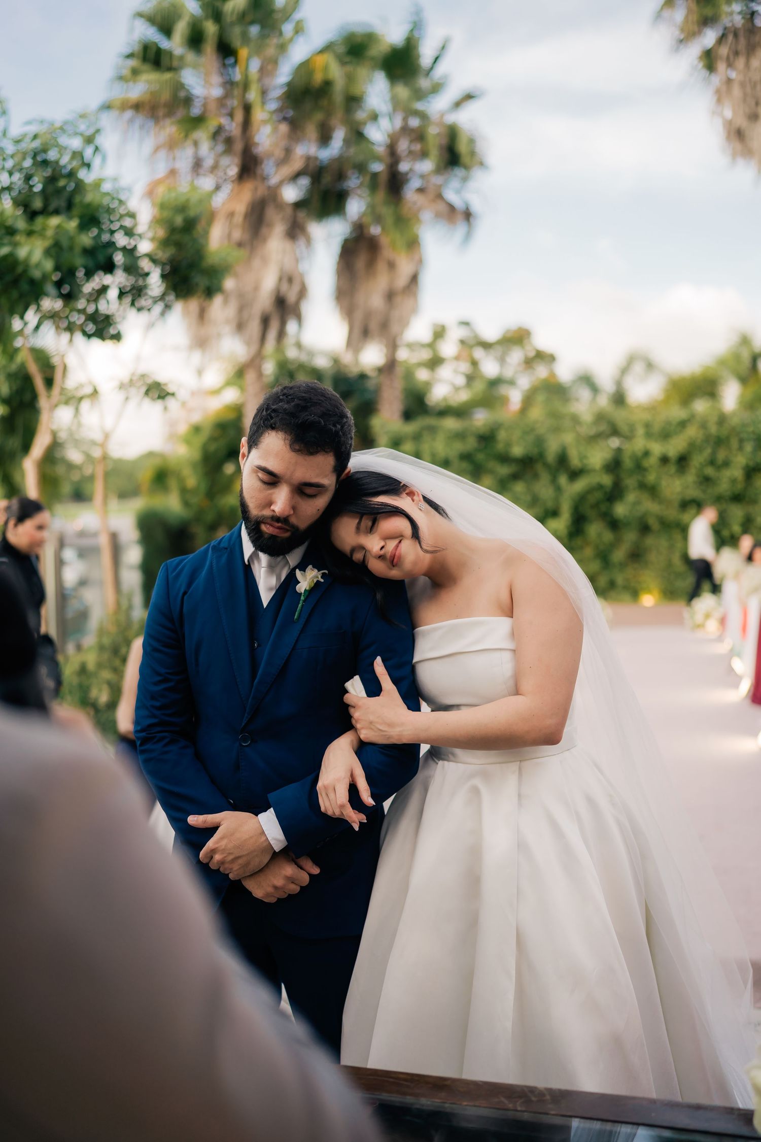 Intimate wedding moment captured under palm trees during an outdoor celebration.