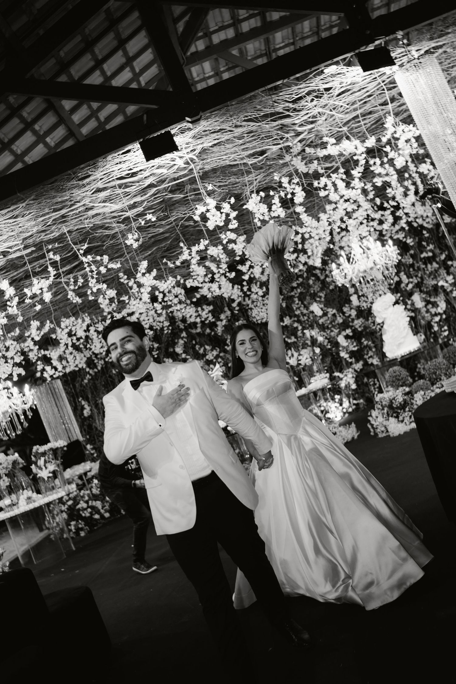 Black and white photo series showing dancers performing in flowing white garments under decorative floral arrangements.