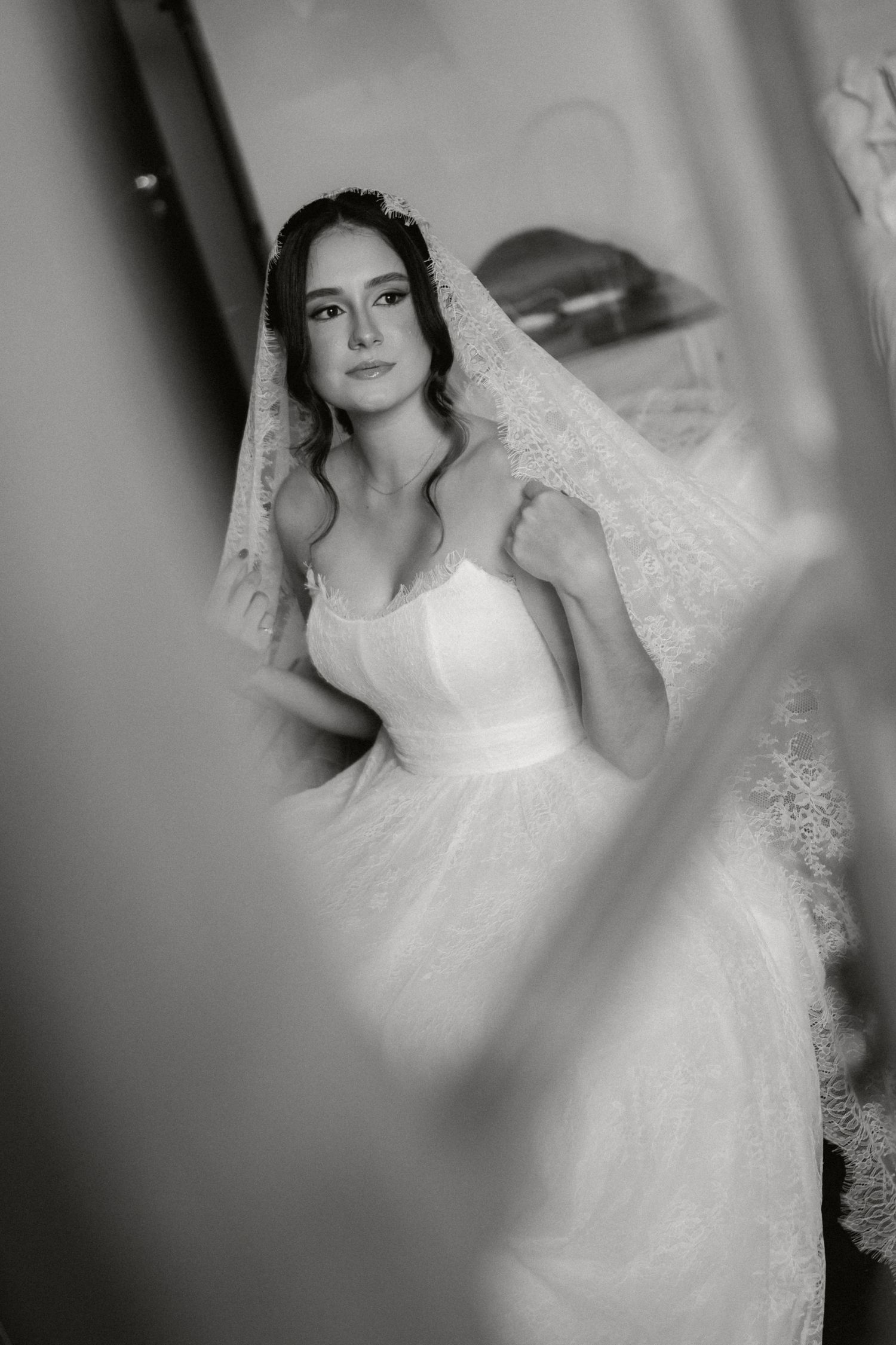 A bride in a white lace wedding dress poses gracefully in a series of romantic black and white portraits.