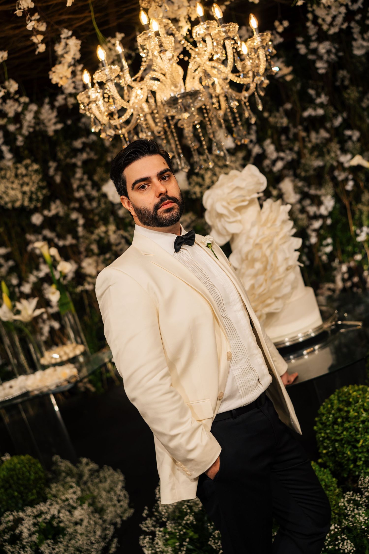 An elegant wedding reception setup with crystal chandeliers and floral arrangements against a dark background.