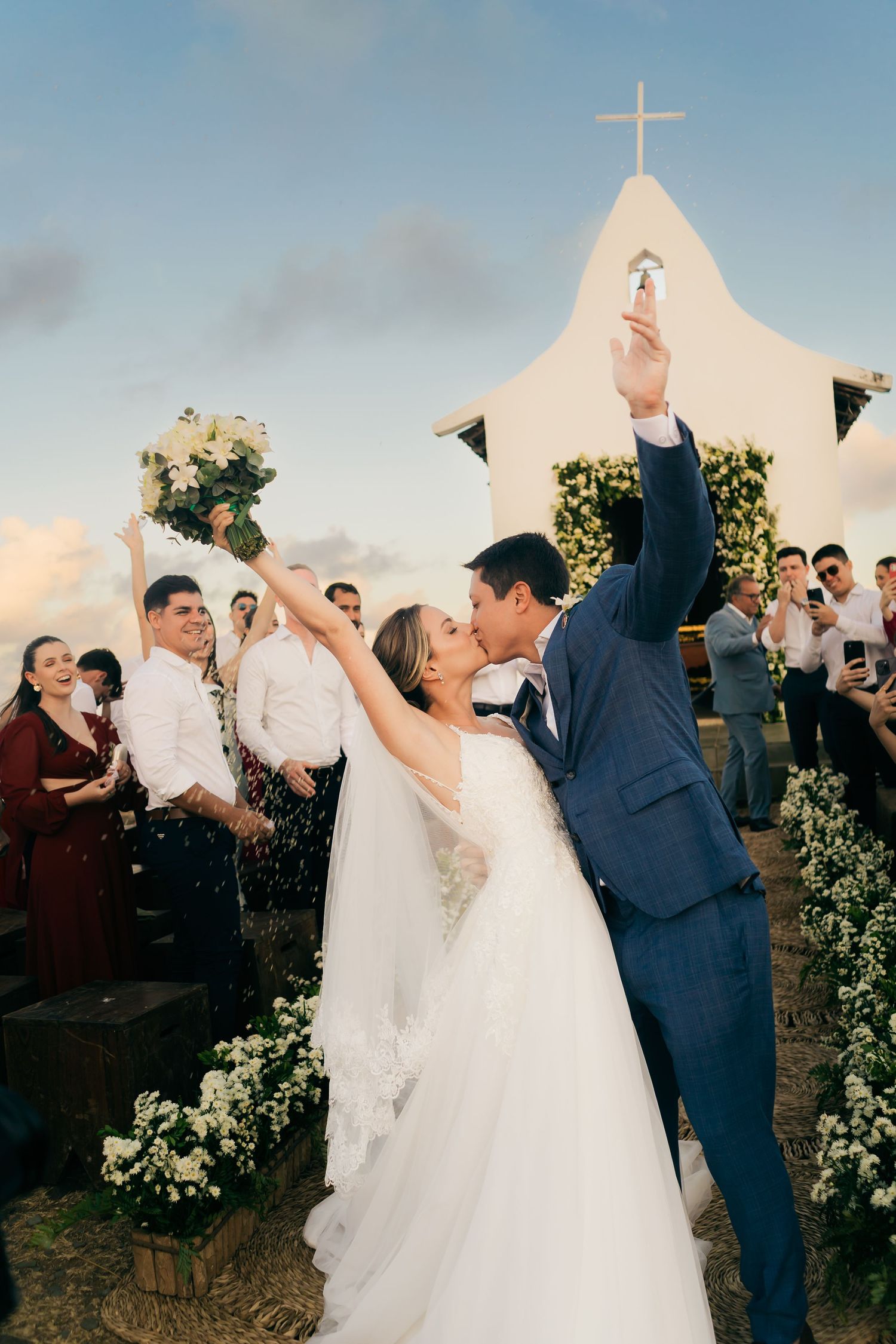 Celebratory moment at a church wedding with white floral decorations and a cross in the background.