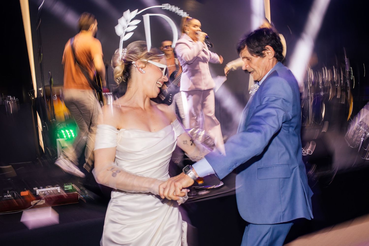 Wedding guests dancing and celebrating on a dimly lit dance floor.