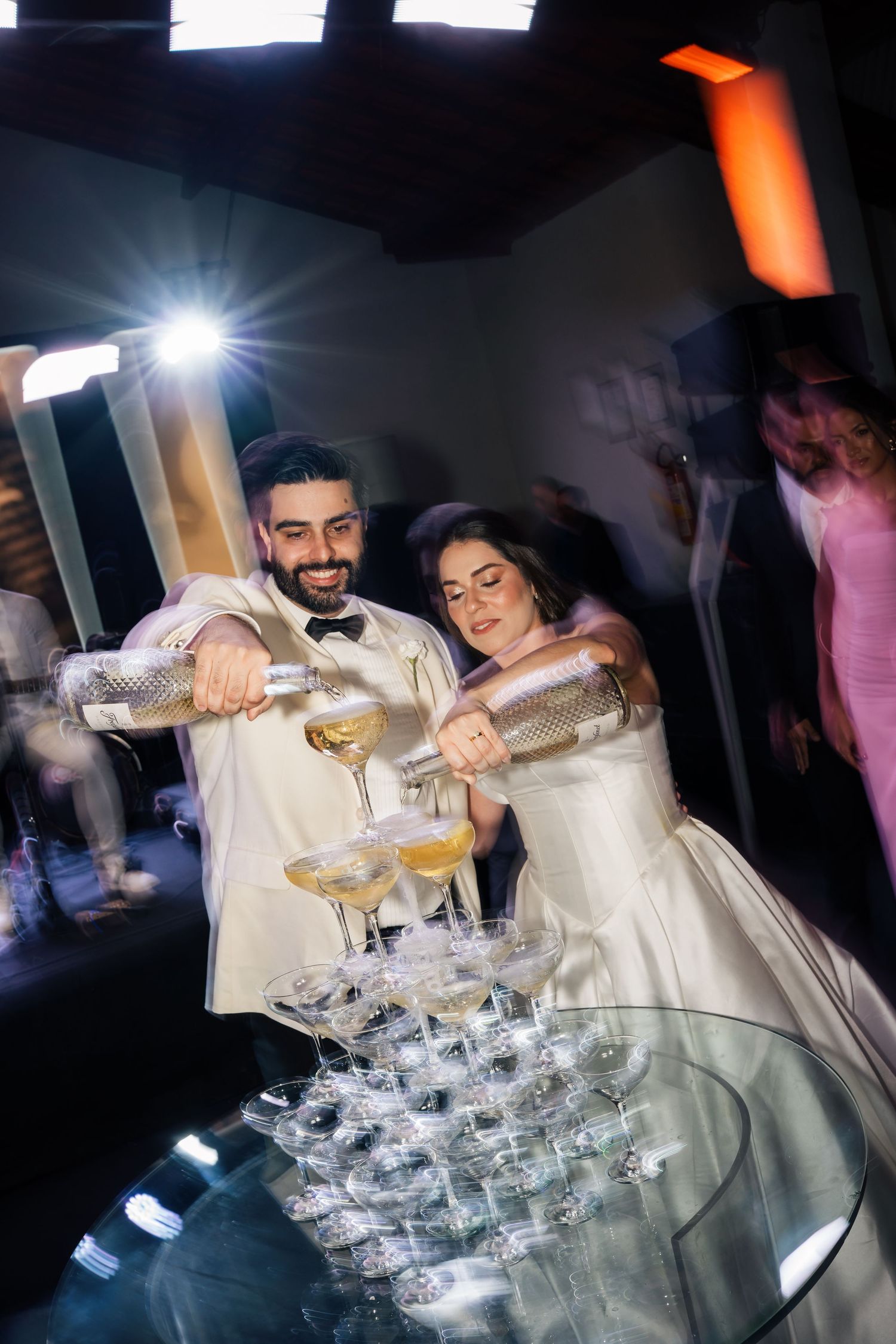 Champagne being poured into a tower of stacked glasses at an elegant celebration.
