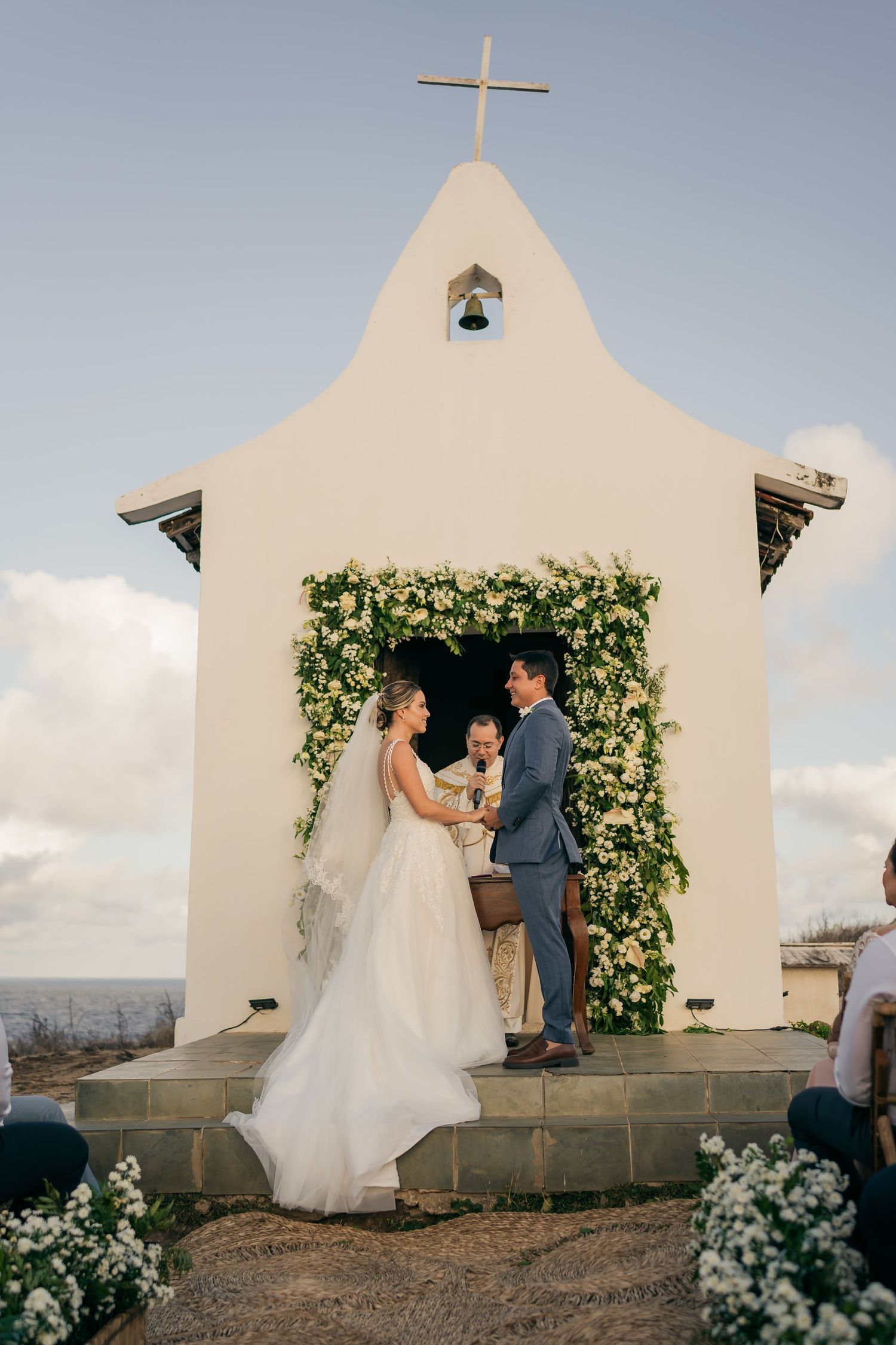 A charming white chapel decorated with greenery serves as a beautiful wedding ceremony backdrop.