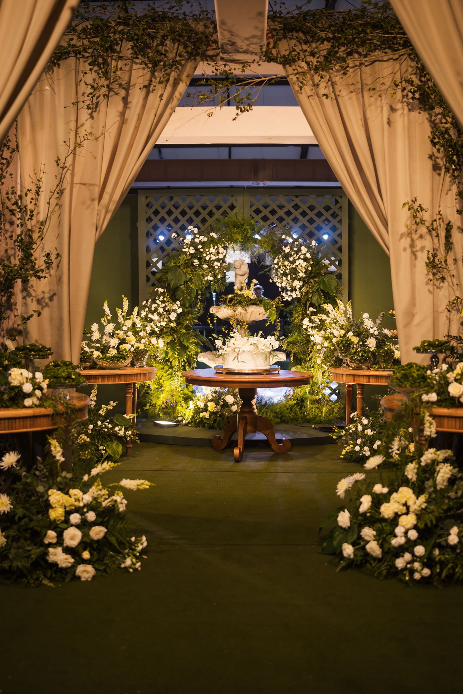 Enchanting wedding reception setup with floral archway, draped fabric, and illuminated decor.