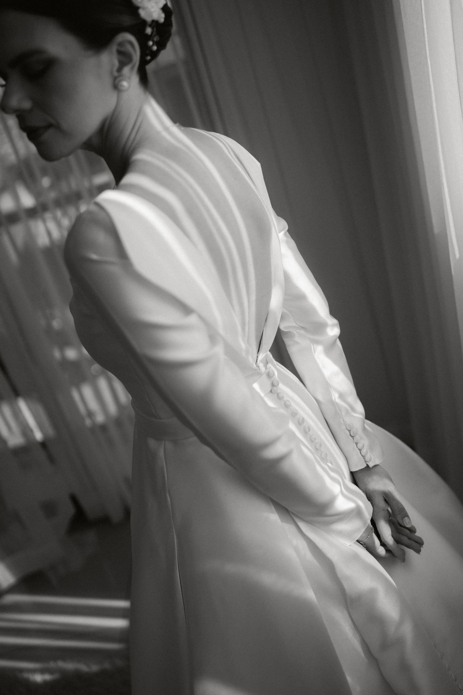 Black and white photograph showing the back detail of an elegant white wedding dress.