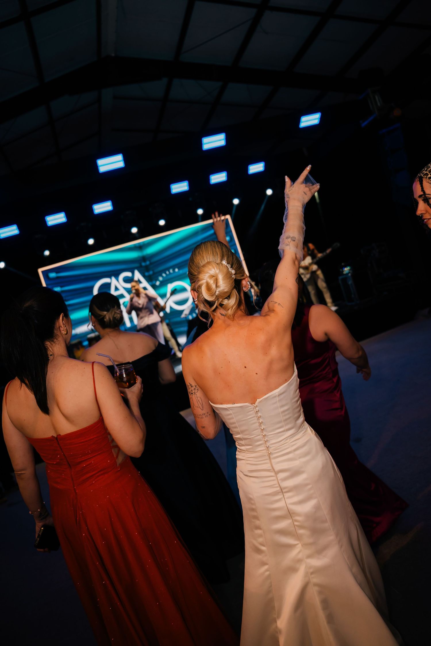 People dancing and celebrating at a party with arms raised under blue lighting.