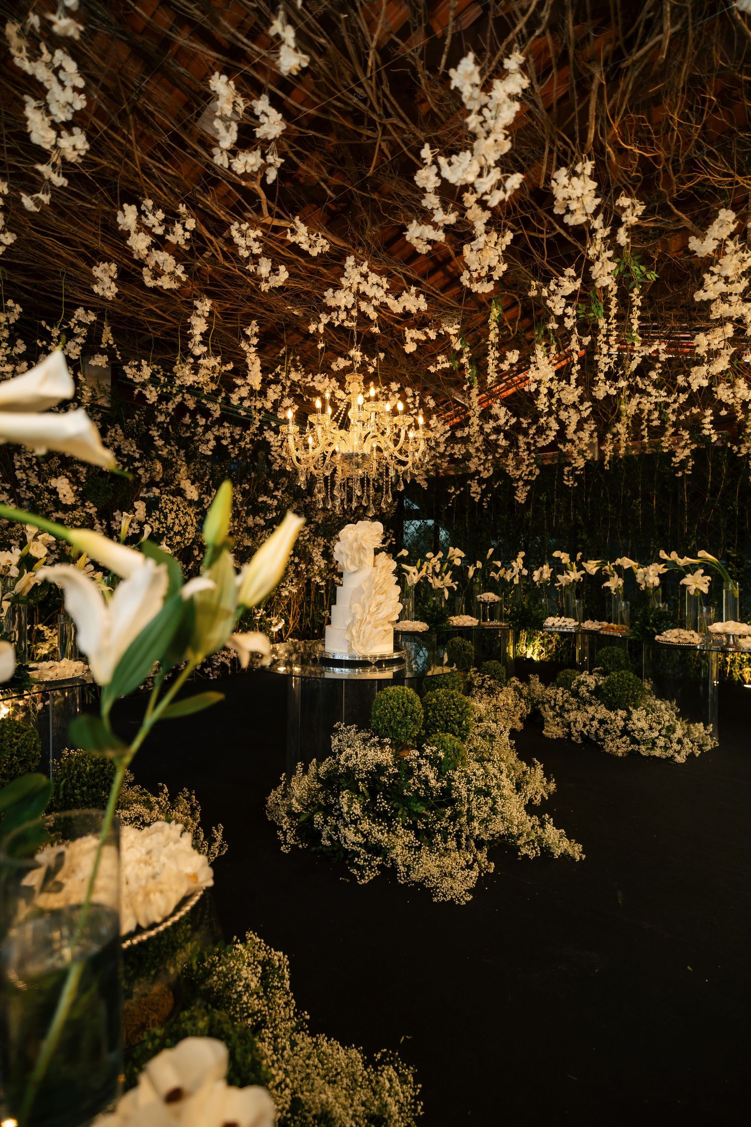 Romantic wedding reception decor with illuminated floral installations and twinkling lights.