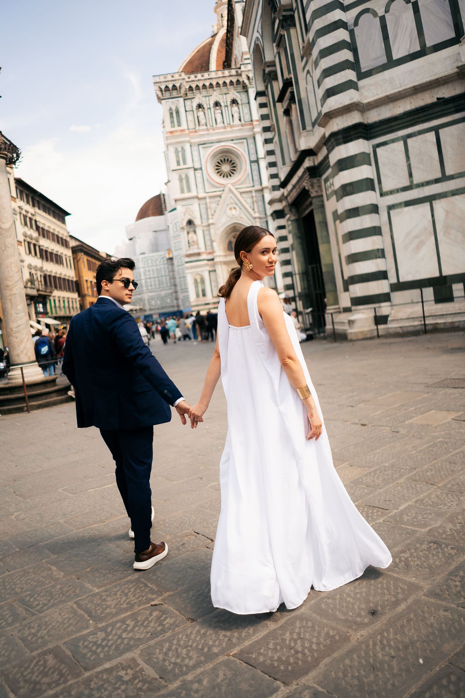 A couple in wedding attire walks along the historic streets of Florence near the Duomo cathedral.