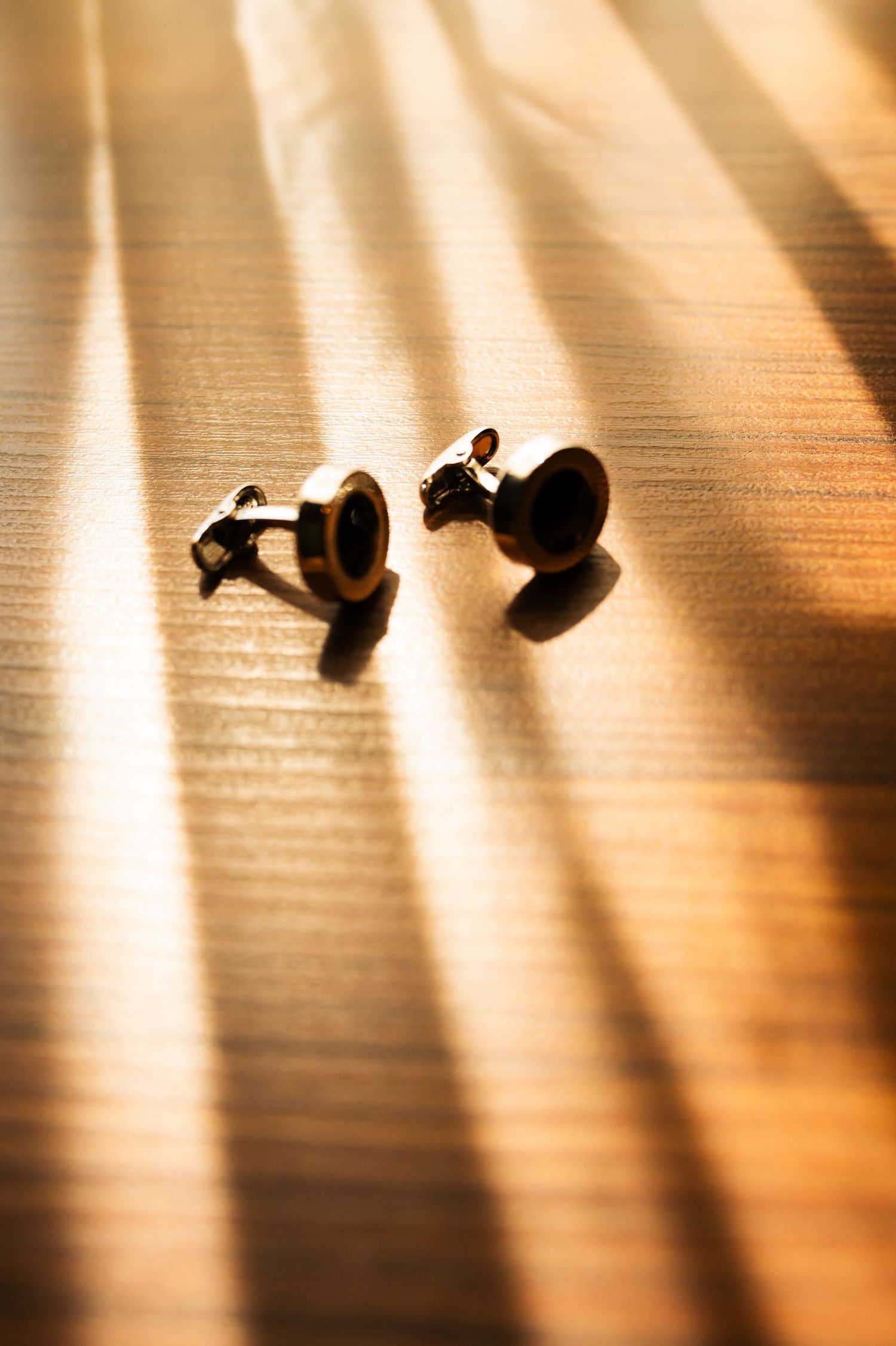 Silhouettes of spotlights cast dramatic shadows and beams across a wooden surface in warm lighting.