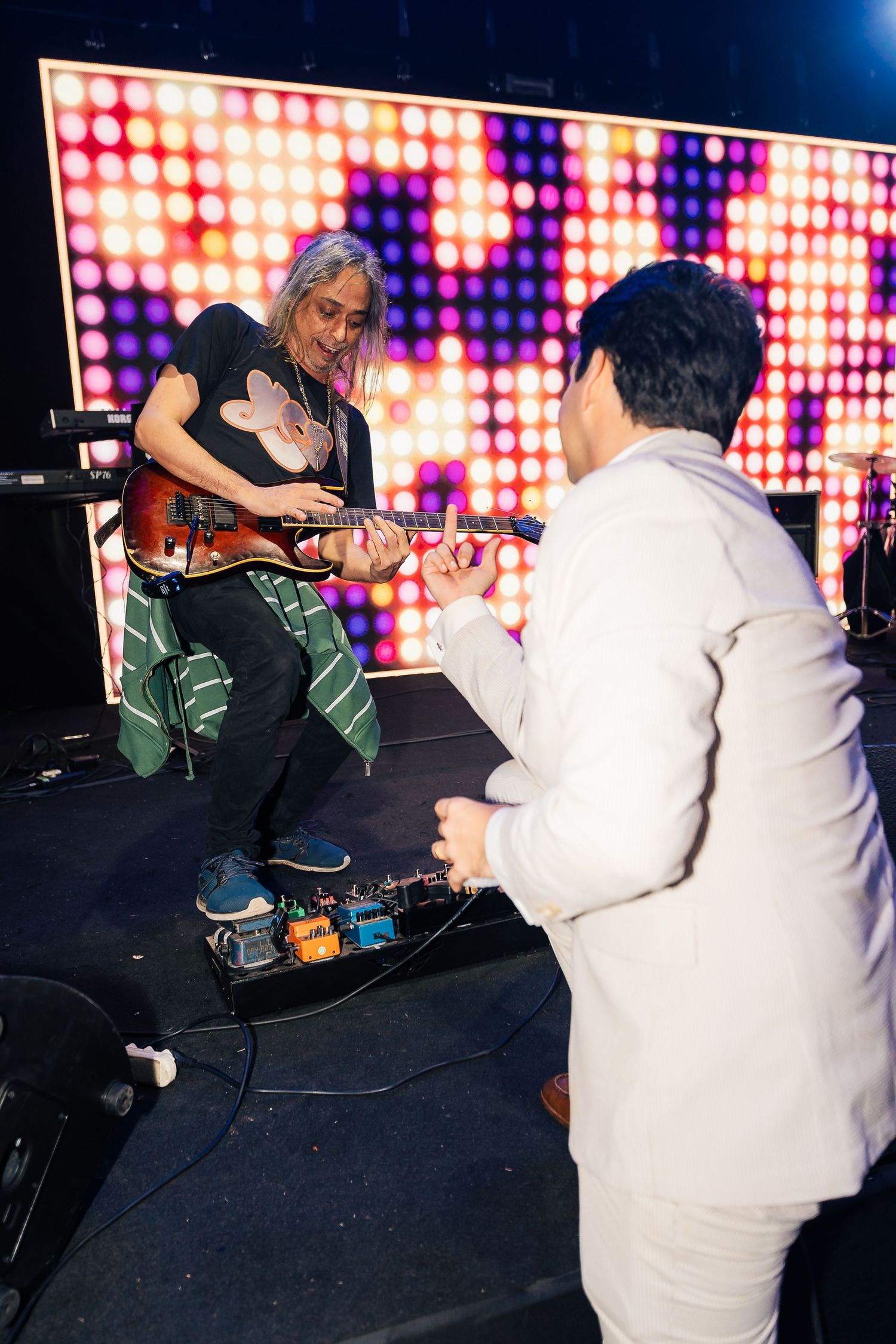 A colorful LED wall provides vibrant backdrop for performers at a wedding reception.