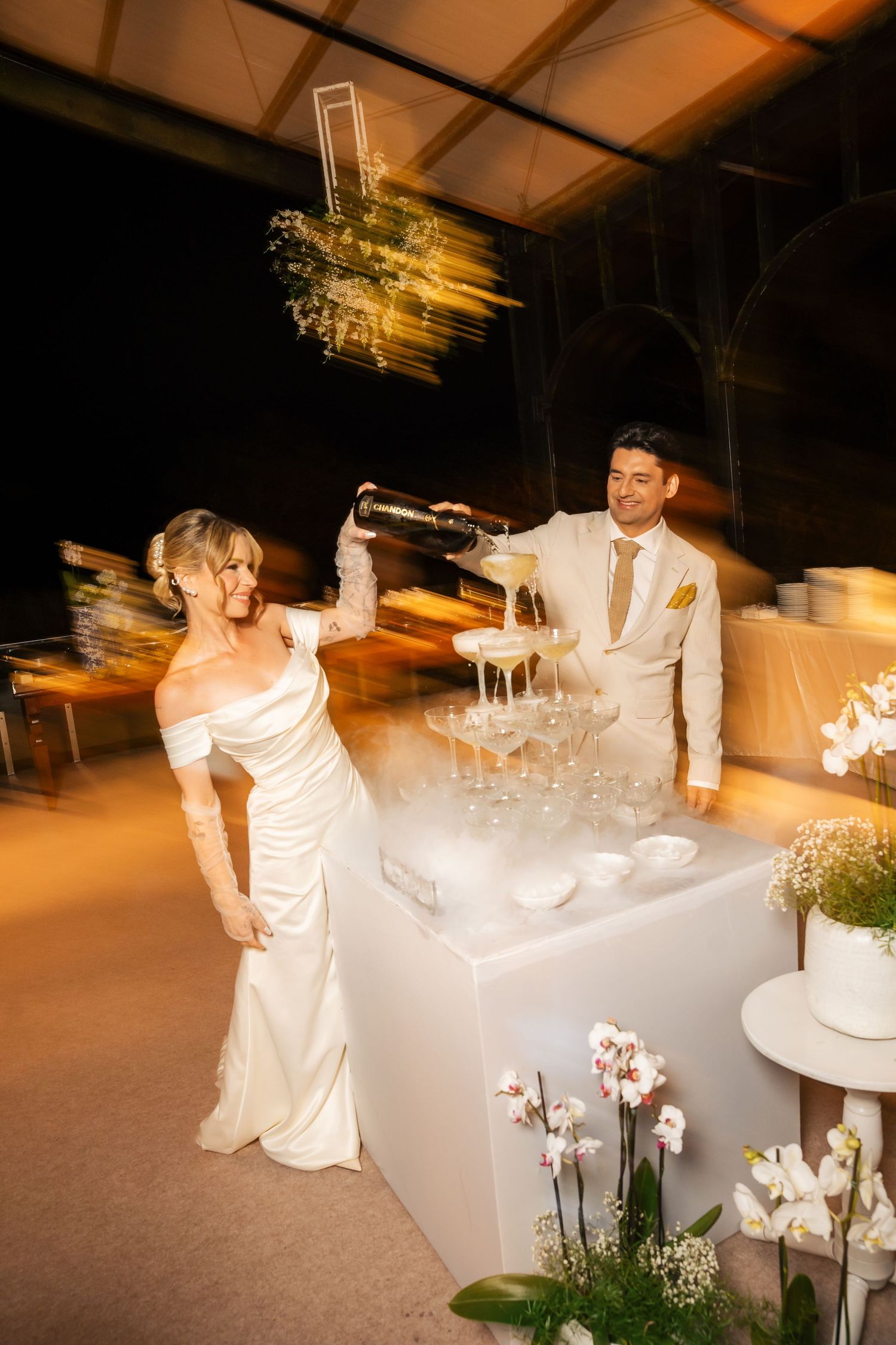 An elegant wedding reception setup with white decor and glowing ambient lighting.