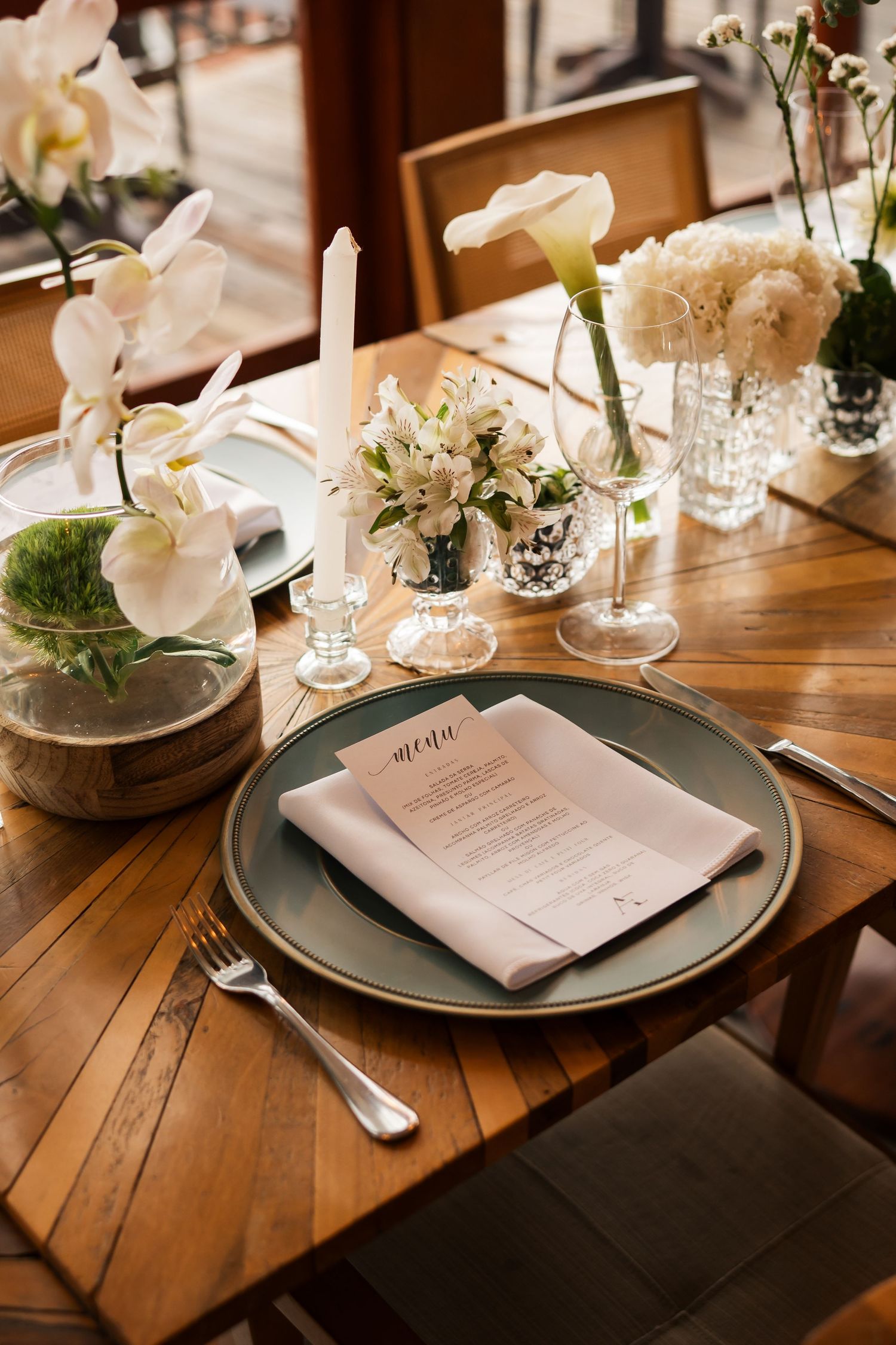 Elegant table setting with white orchids and menu cards on rustic wooden tables.