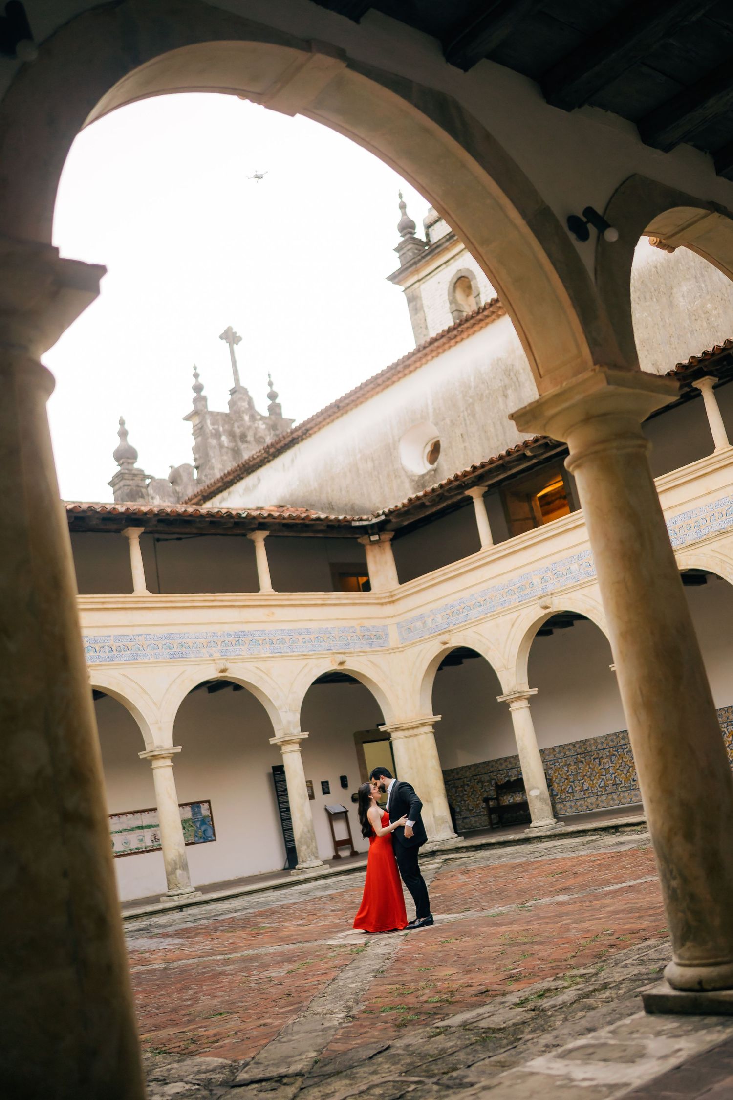 A courtyard with white columns and arches featuring a couple in formal attire.