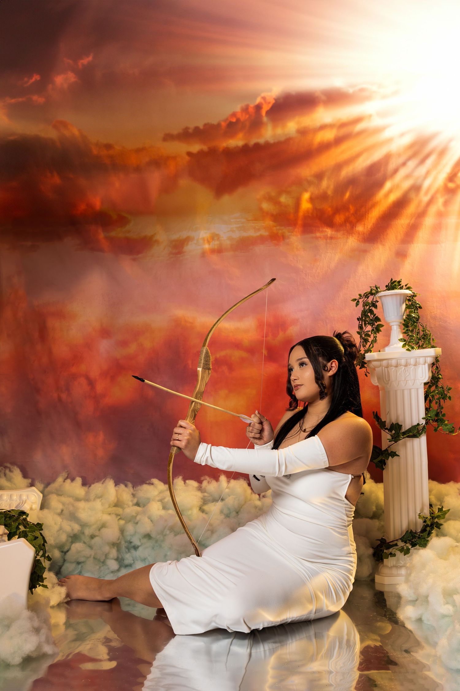 Fantasy portrait with bow and arrow against dramatic sunset sky and classical columns.