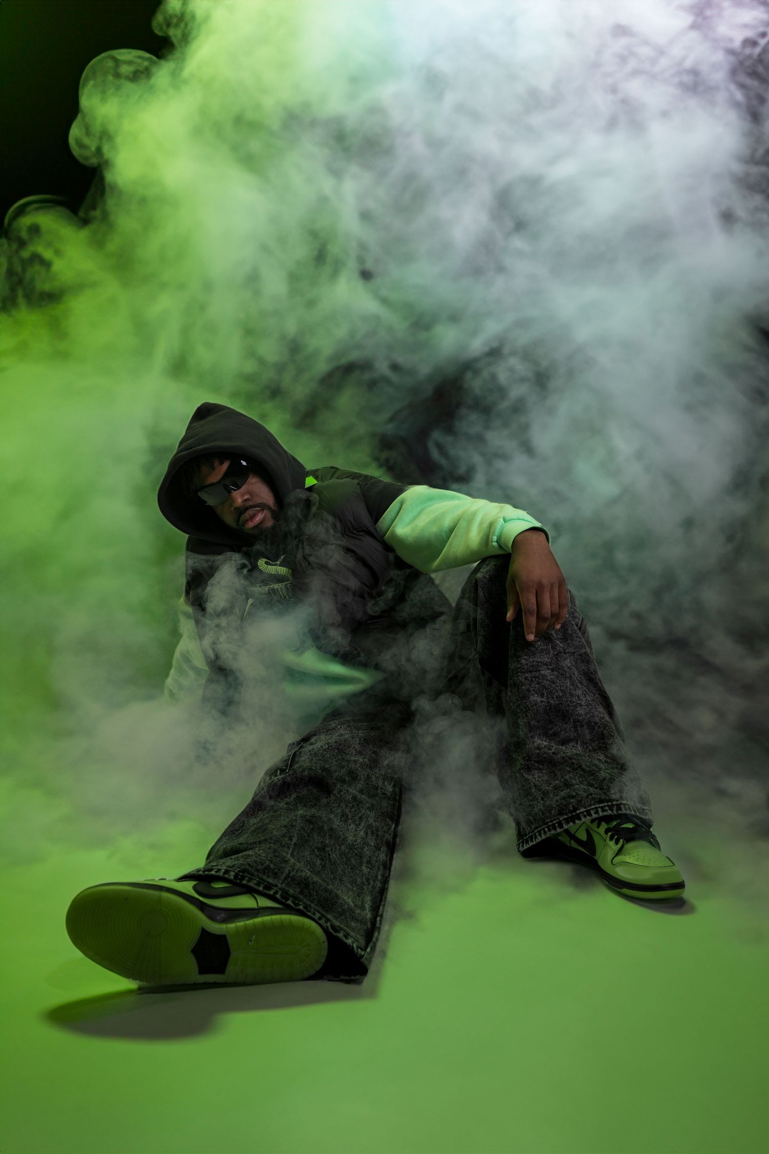 A figure in dark clothing falls backwards dramatically through swirling green and white smoke effects in a photo sequence.