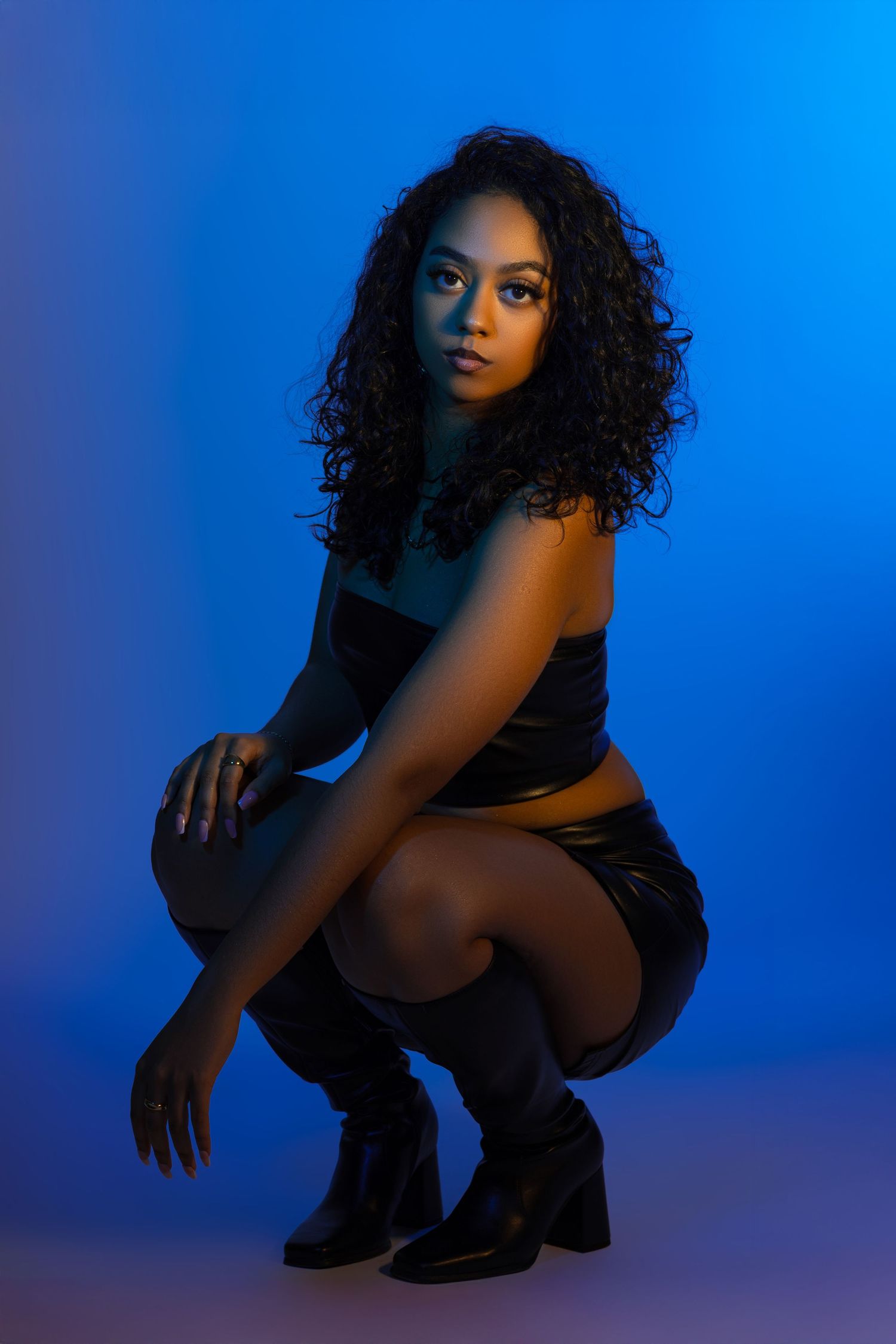 Artistic portrait series against blue backdrop showing dramatic poses in dark attire with moody lighting effects.