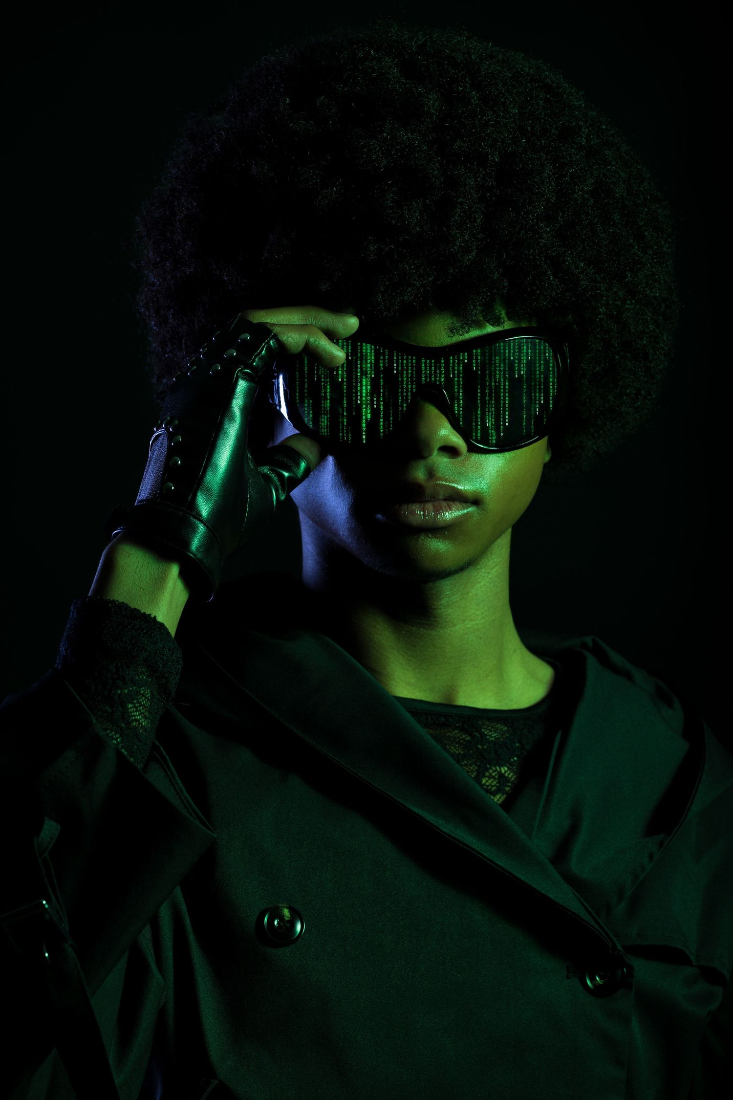 Woman with afro hairstyle wearing futuristic green digital matrix glasses in dark cyberpunk style portrait.