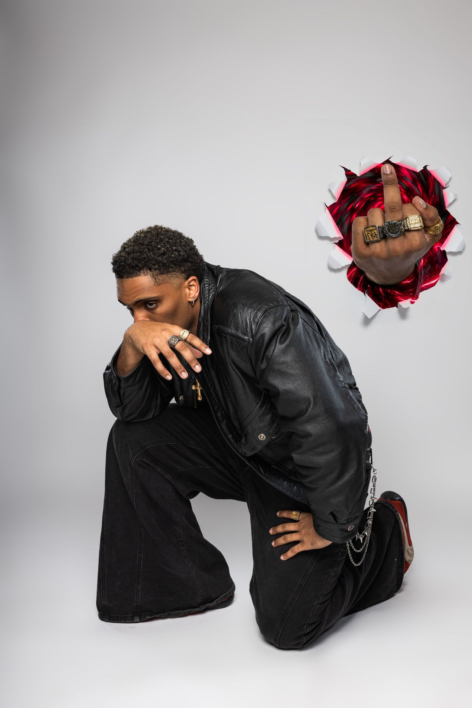 A person in black clothing crouches down in a series of dramatic poses against a white studio backdrop.