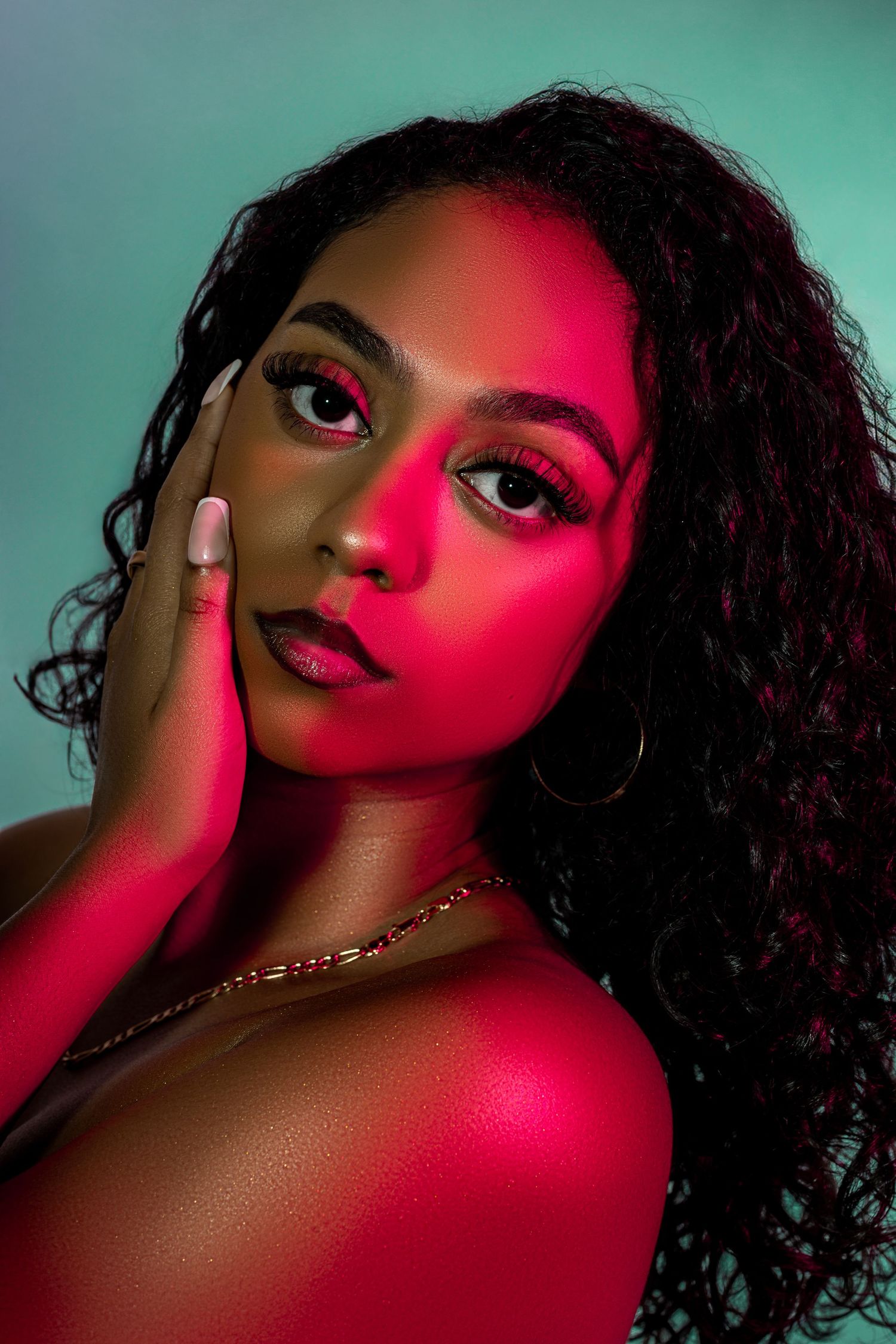 Beauty portrait with dramatic red and teal lighting creating vibrant color contrast.