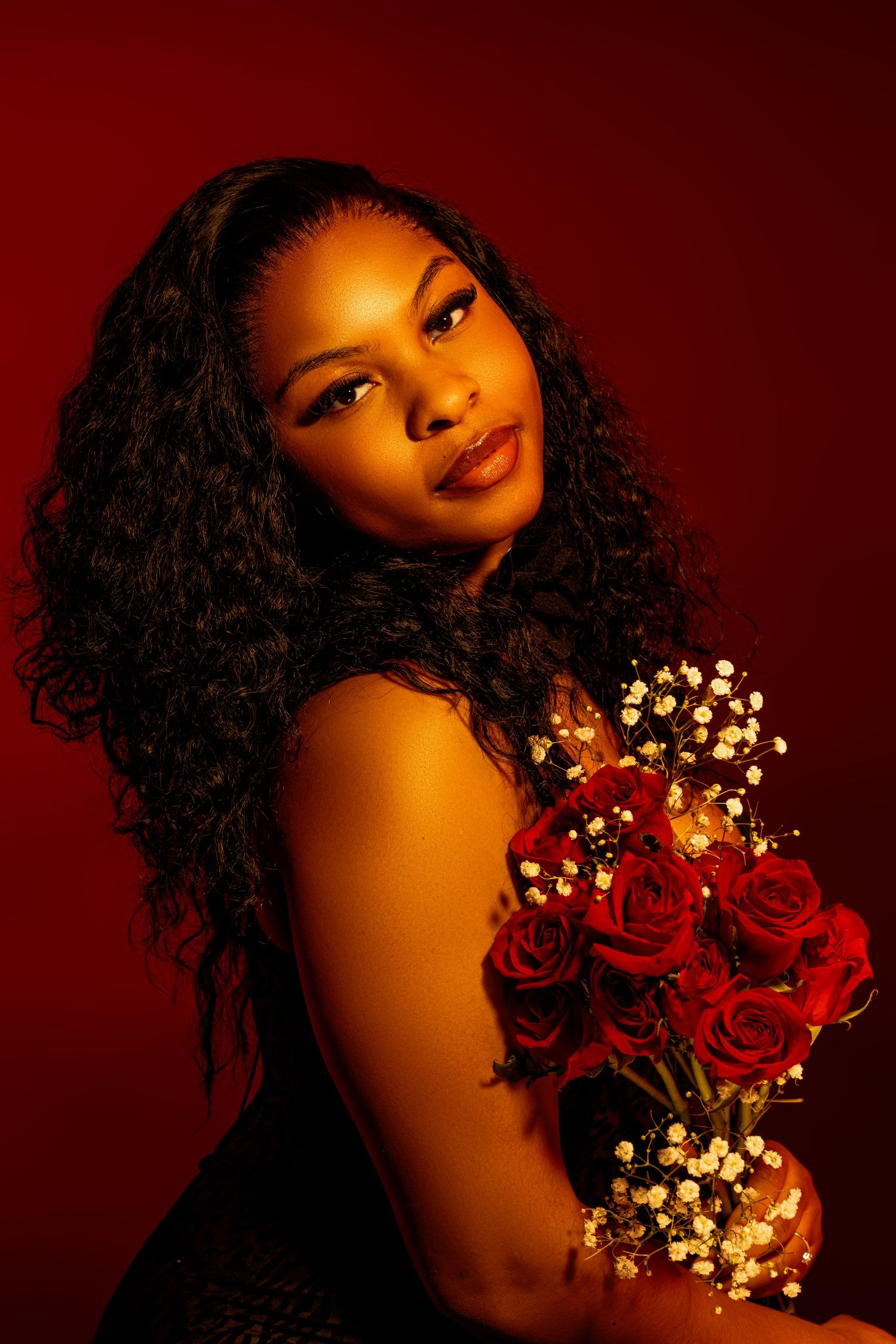Romantic portrait with red roses and baby's breath against deep red background.